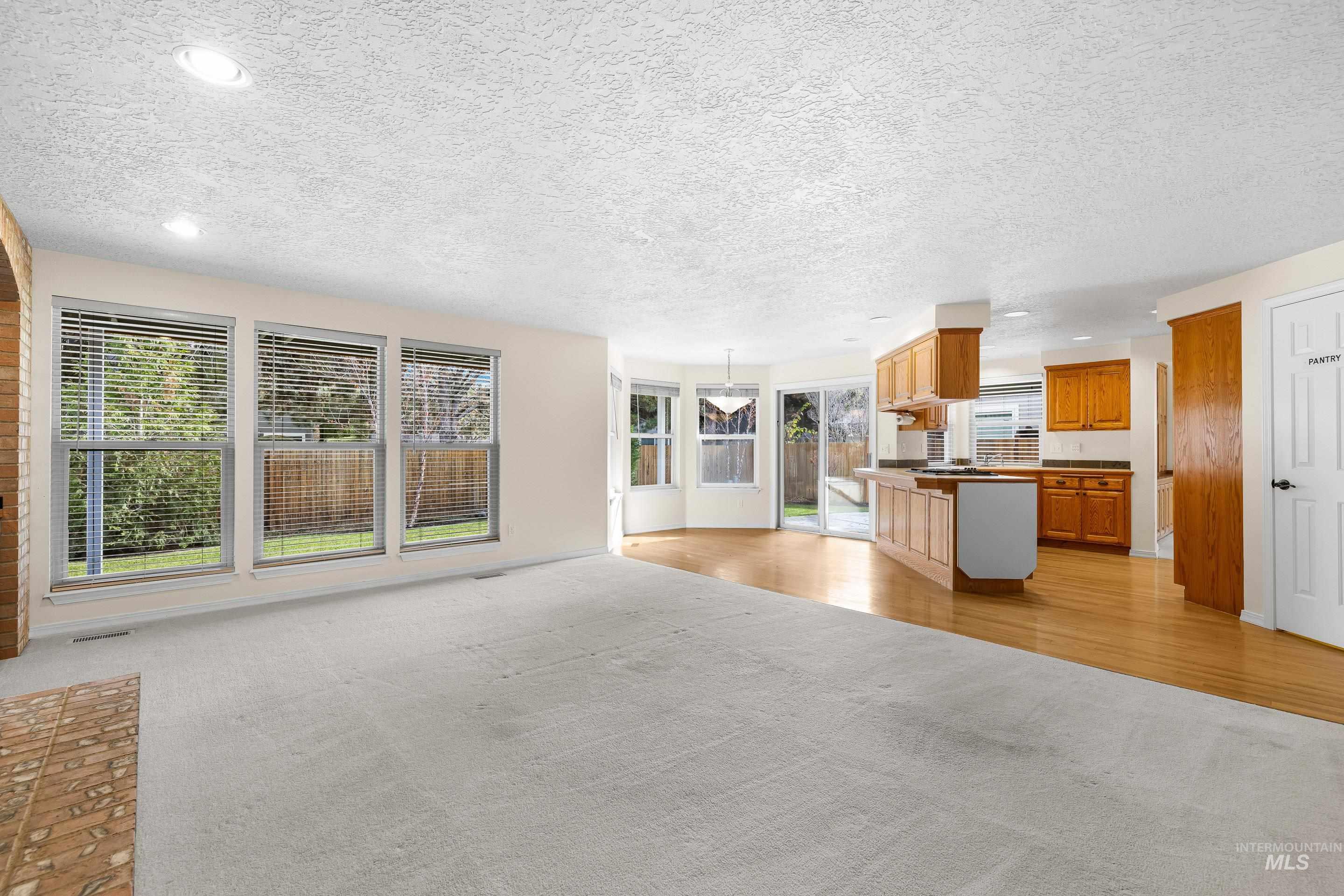 Unfurnished living room featuring a textured ceiling, light colored carpet, and recessed lighting