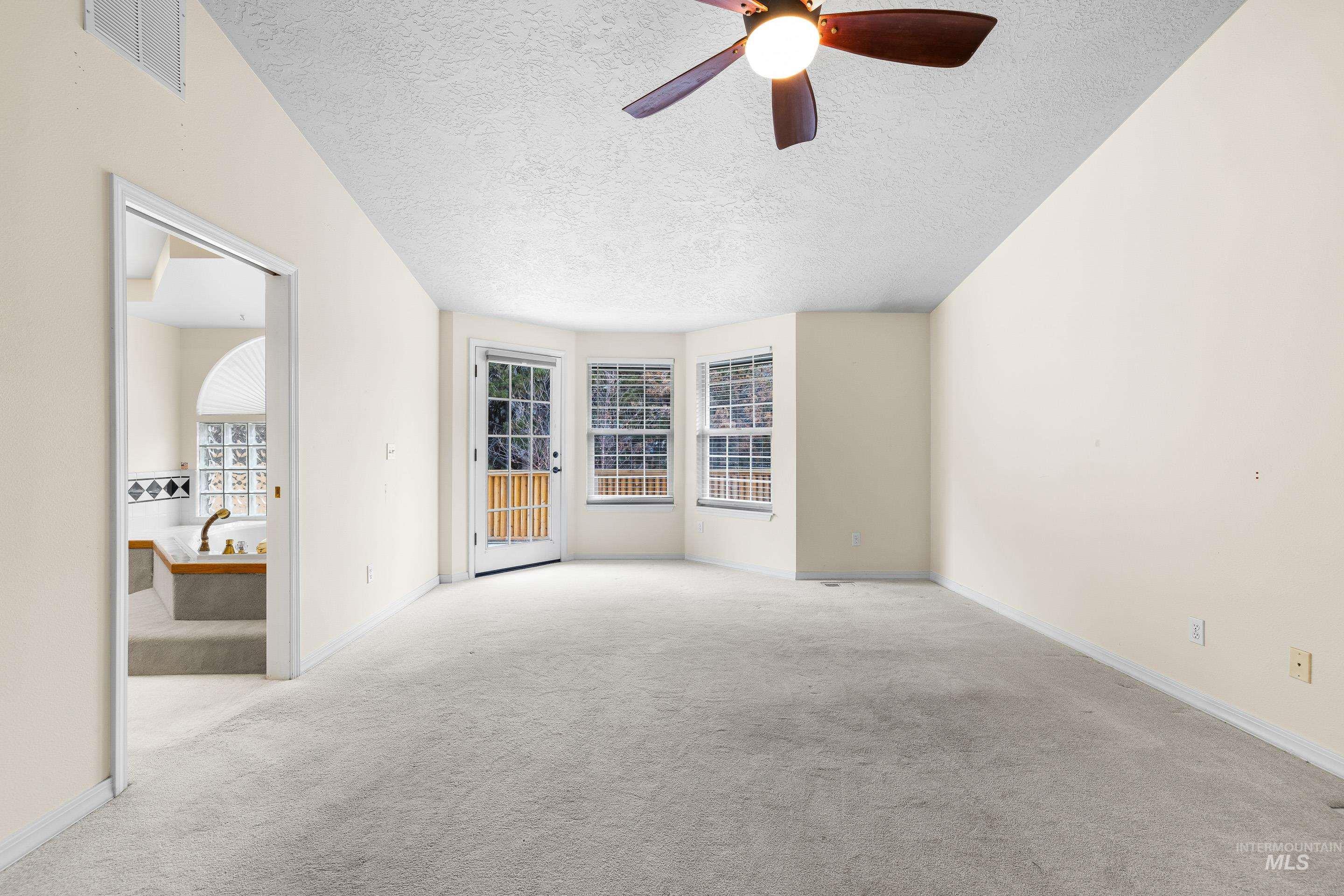 Carpeted empty room featuring a textured ceiling and ceiling fan