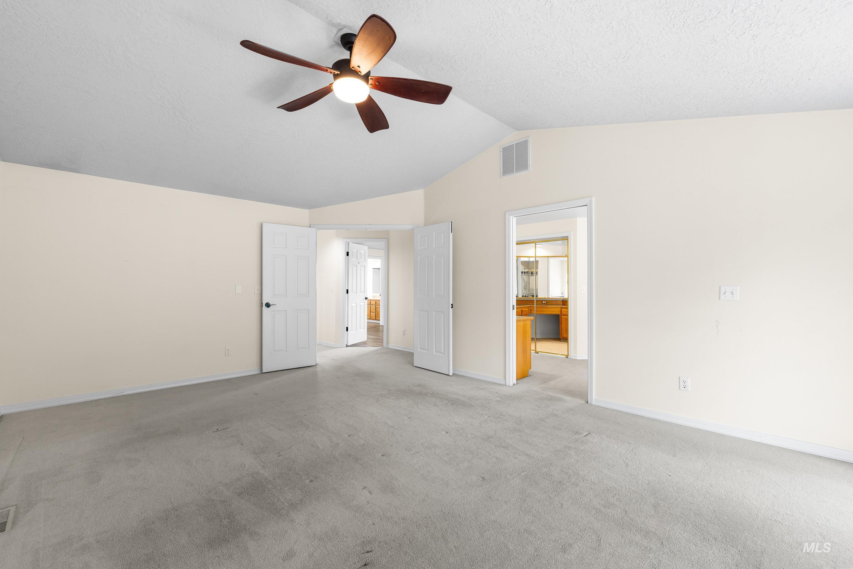 Unfurnished bedroom with vaulted ceiling, connected bathroom, a ceiling fan, and carpet floors