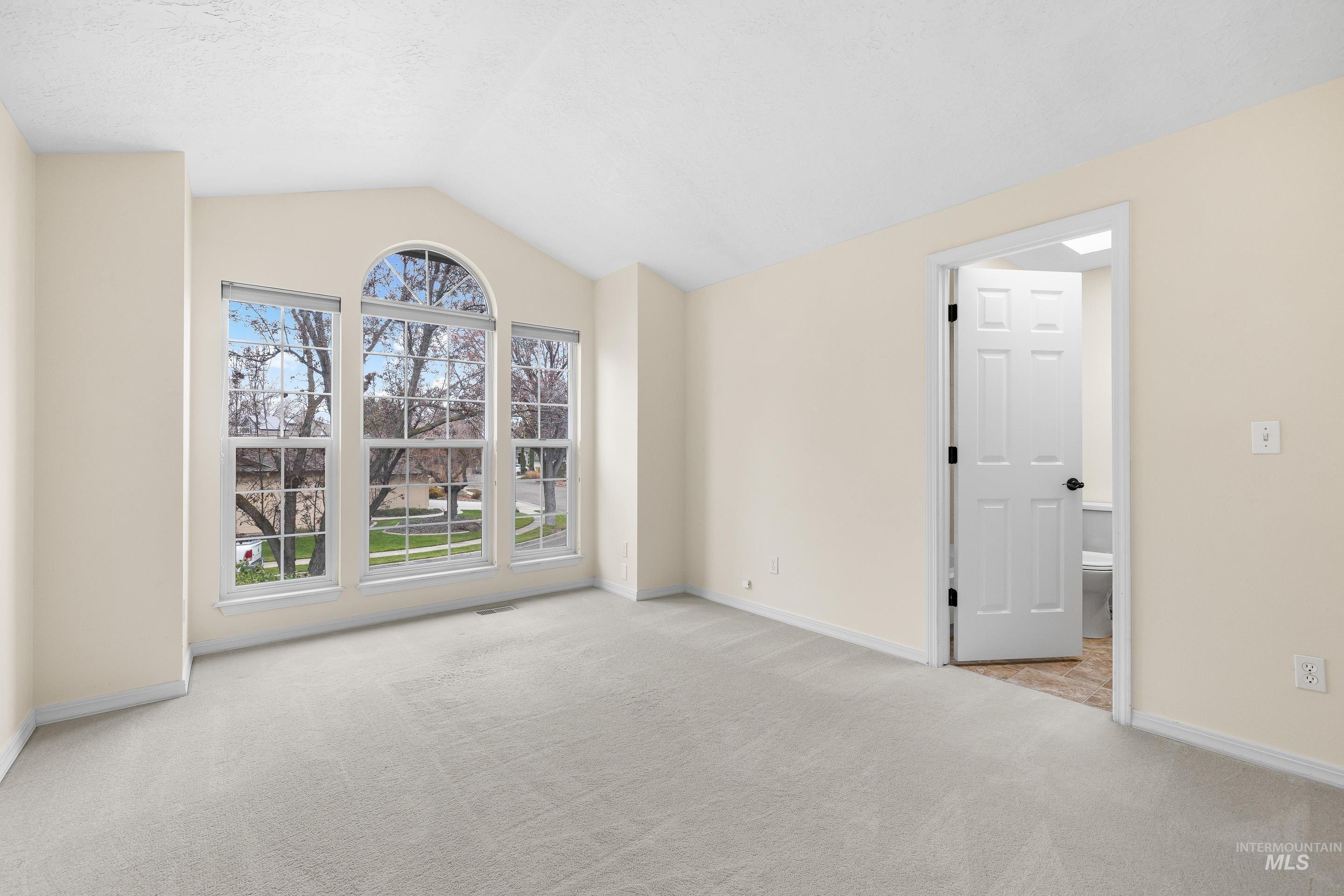 Empty room with light colored carpet and lofted ceiling