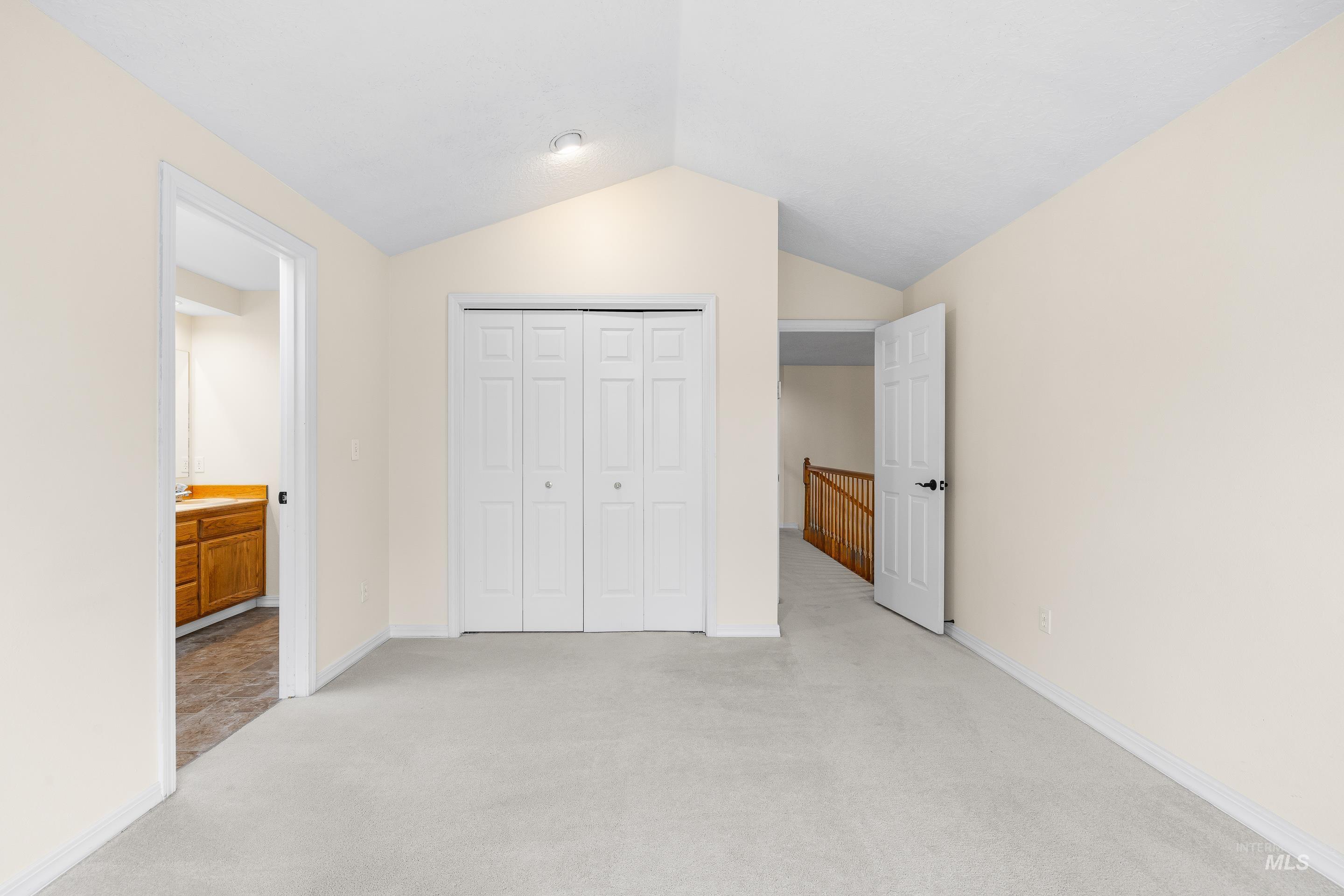 Unfurnished bedroom with light colored carpet, lofted ceiling, and a closet