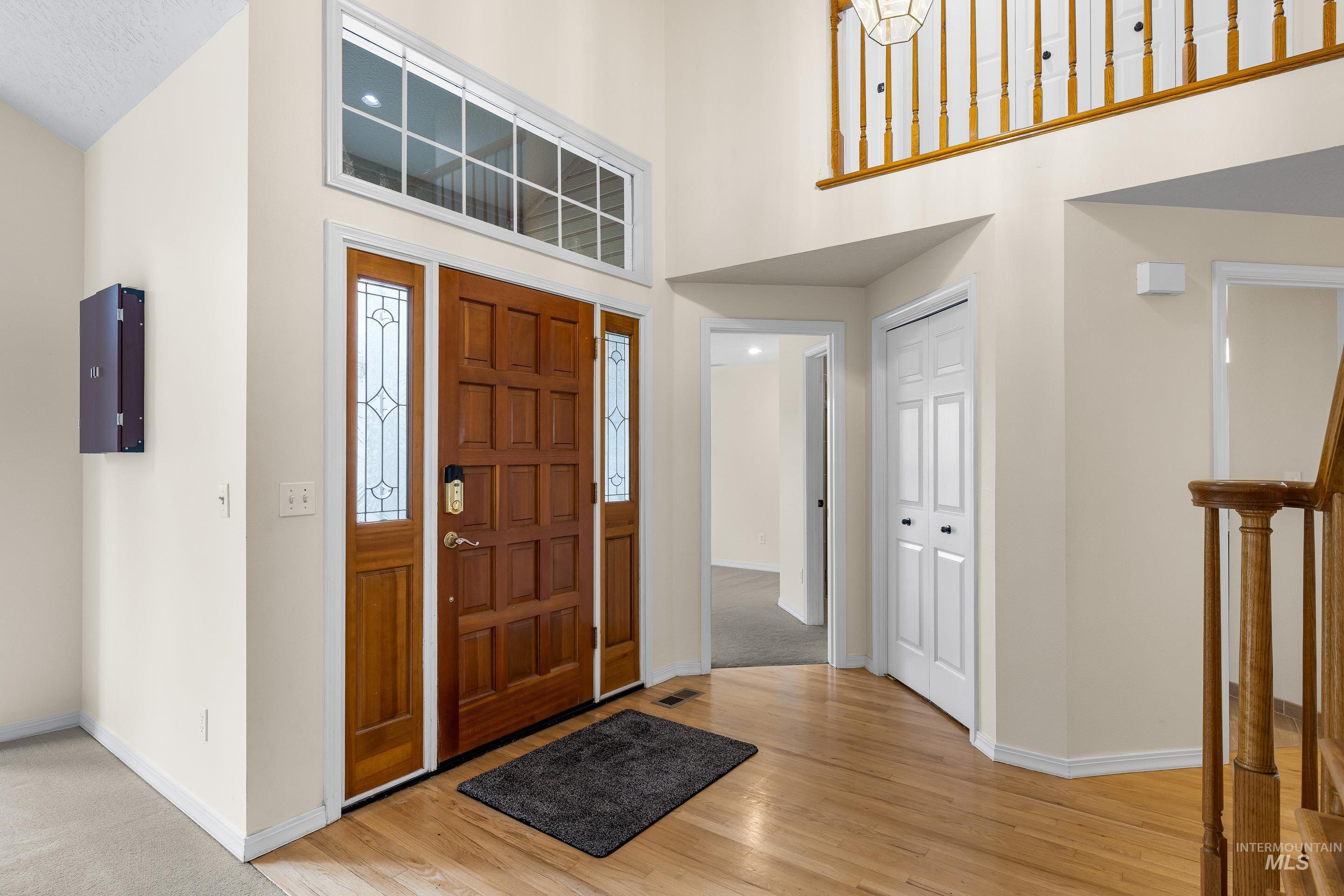 Foyer entrance with light wood finished floors and a high ceiling