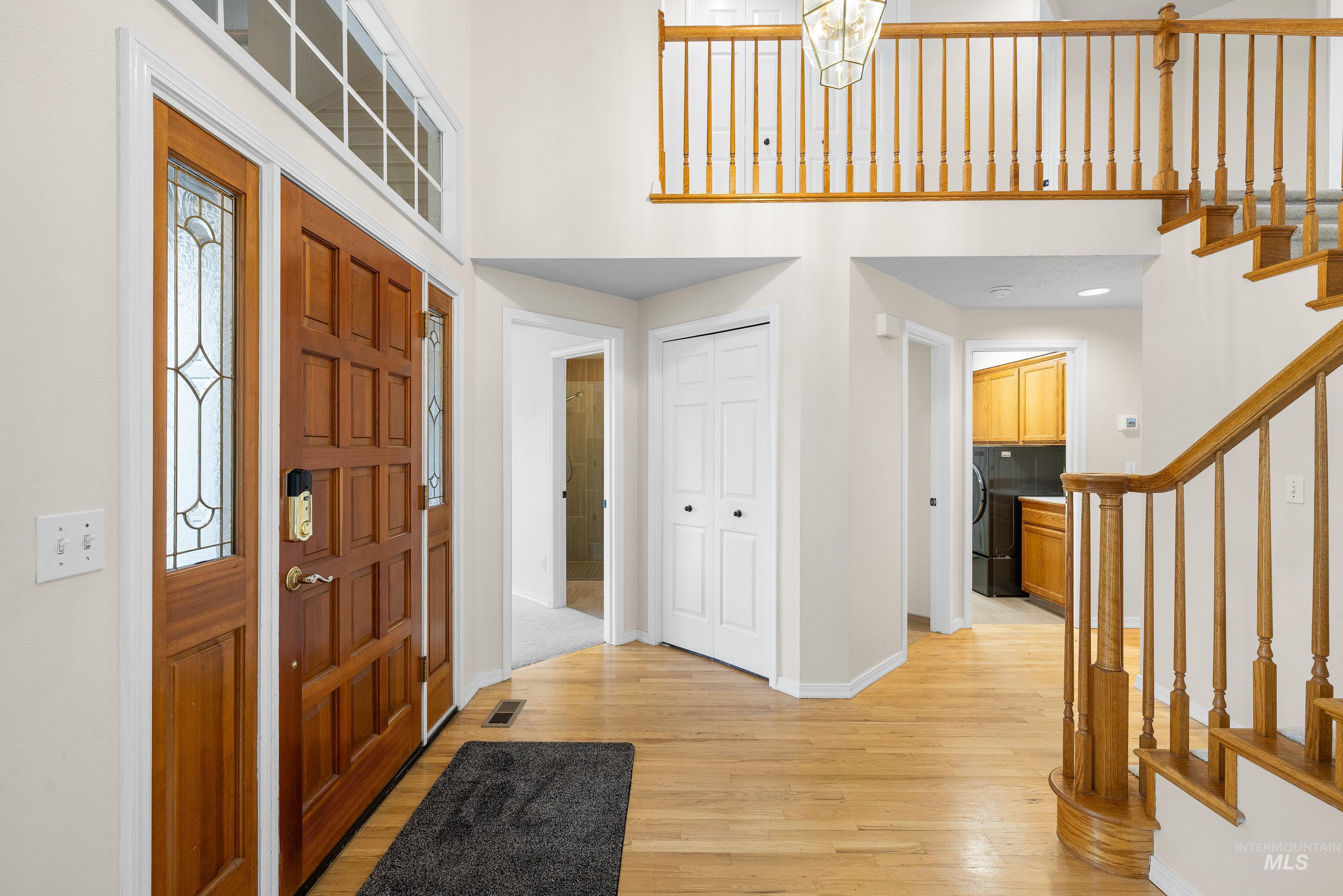 Entryway featuring stairway, light wood-style flooring, and a high ceiling