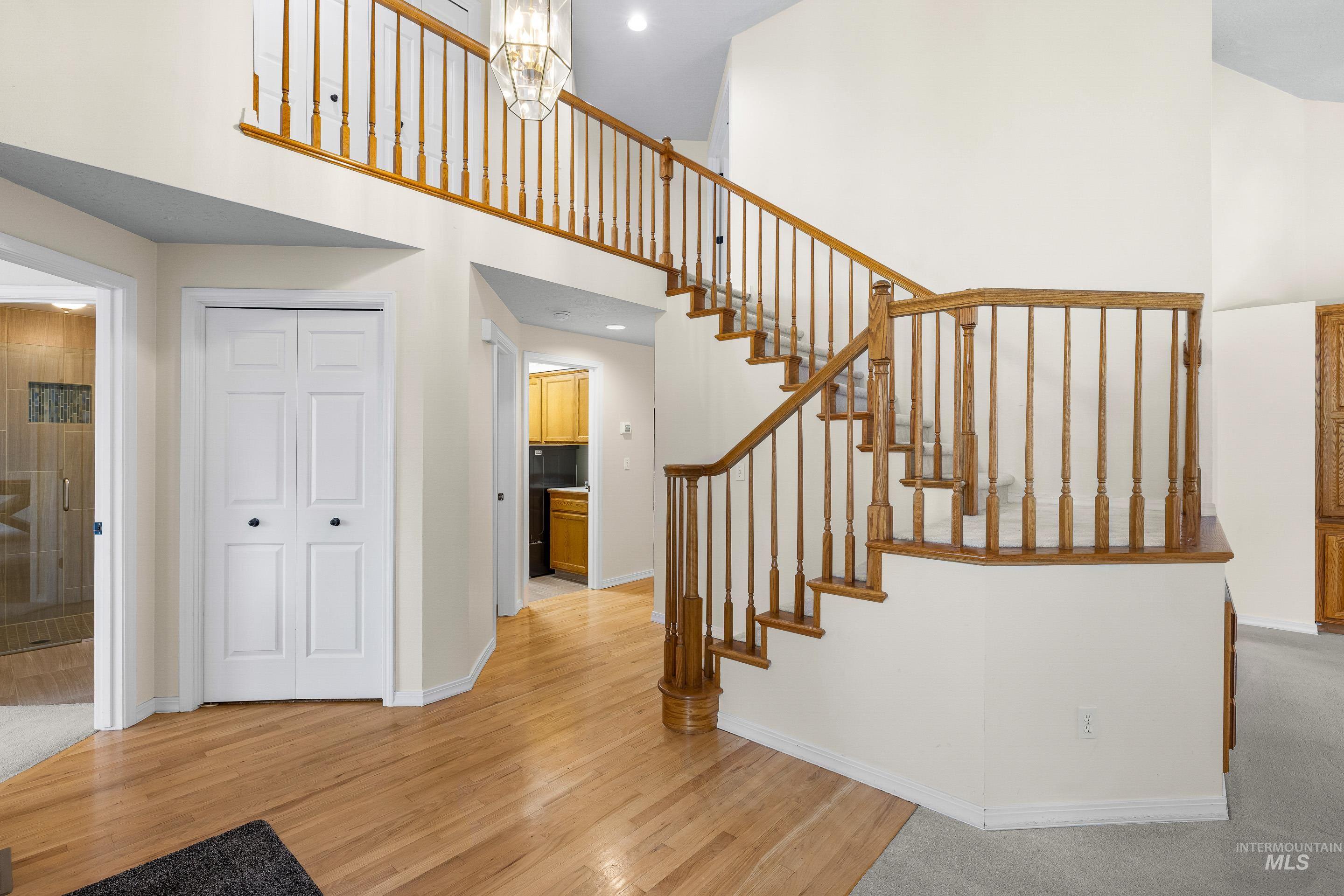 Staircase with a towering ceiling and wood finished floors