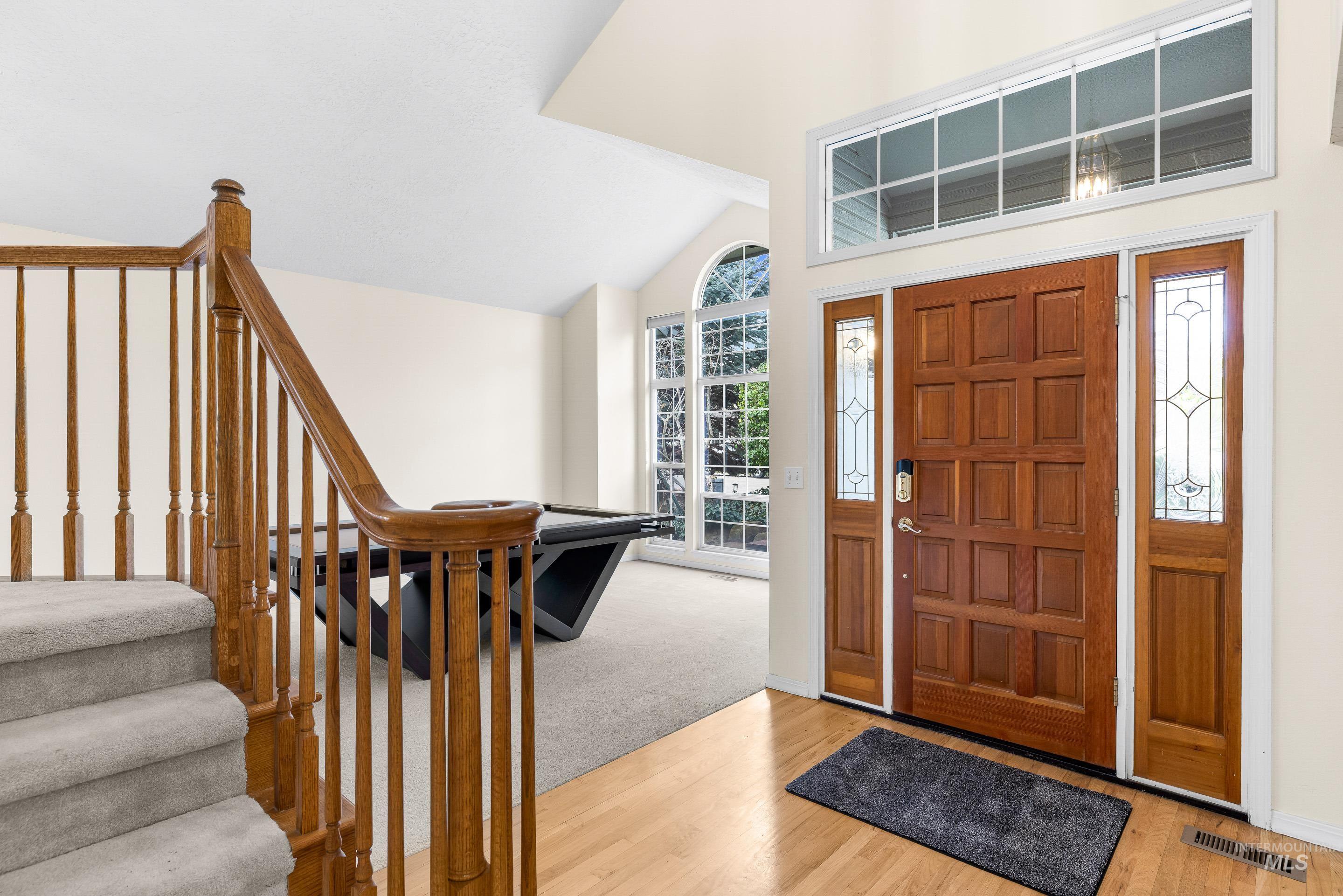 Foyer featuring lofted ceiling, wood finished floors, and stairway