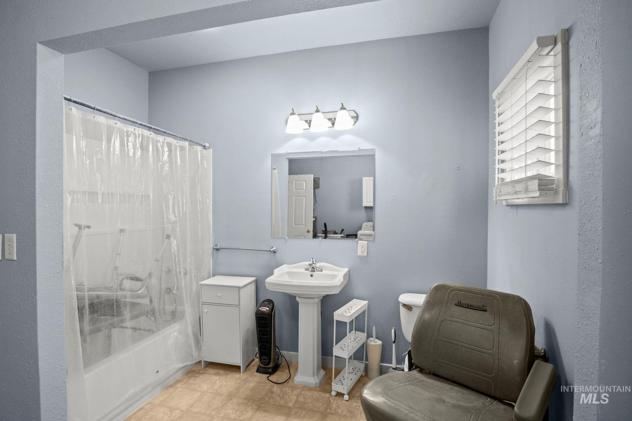 Full bathroom featuring shower / bathtub combination with curtain and a textured wall