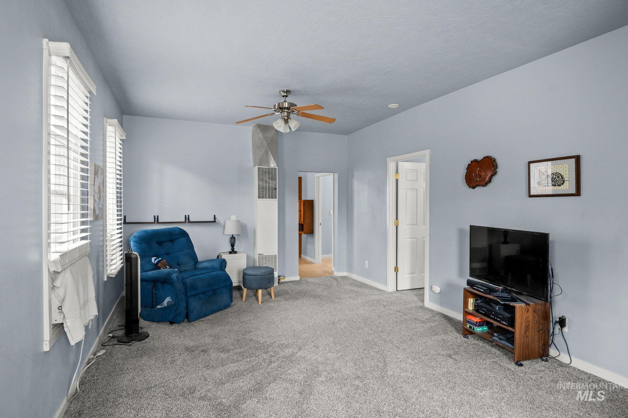 Sitting room featuring carpet, a heating unit, and ceiling fan