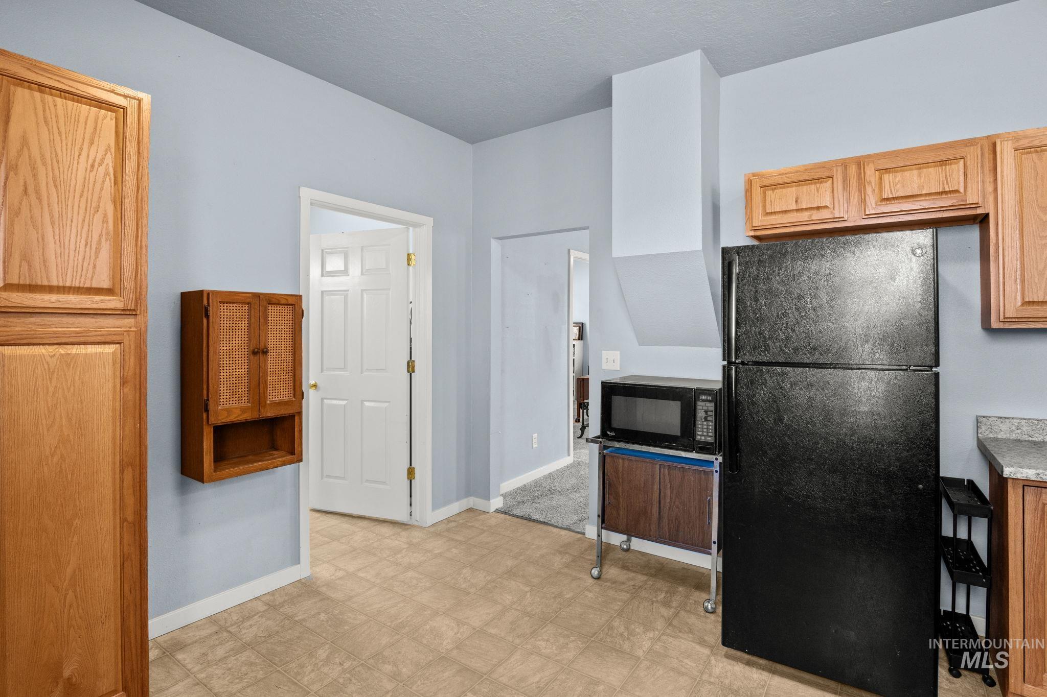 Kitchen with black appliances, light countertops, and light floors