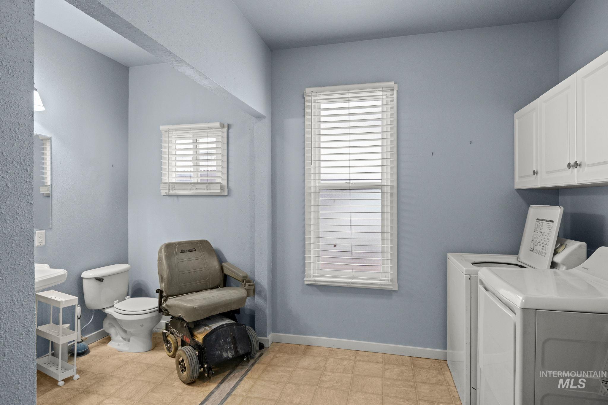 Washroom with light floors, washing machine and dryer, and cabinet space
