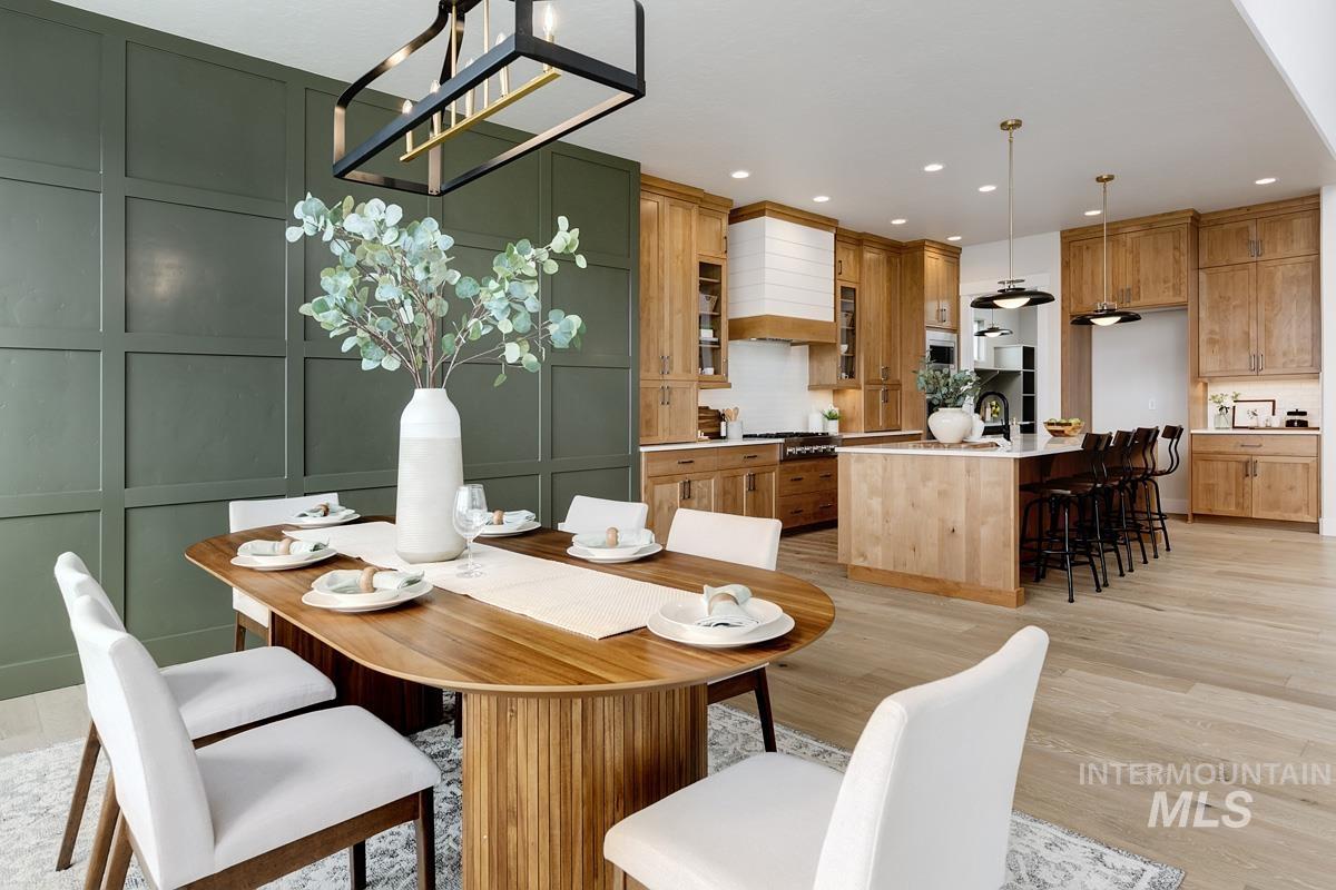 Dining area with a decorative wall, light wood-style flooring, recessed lighting, and a chandelier