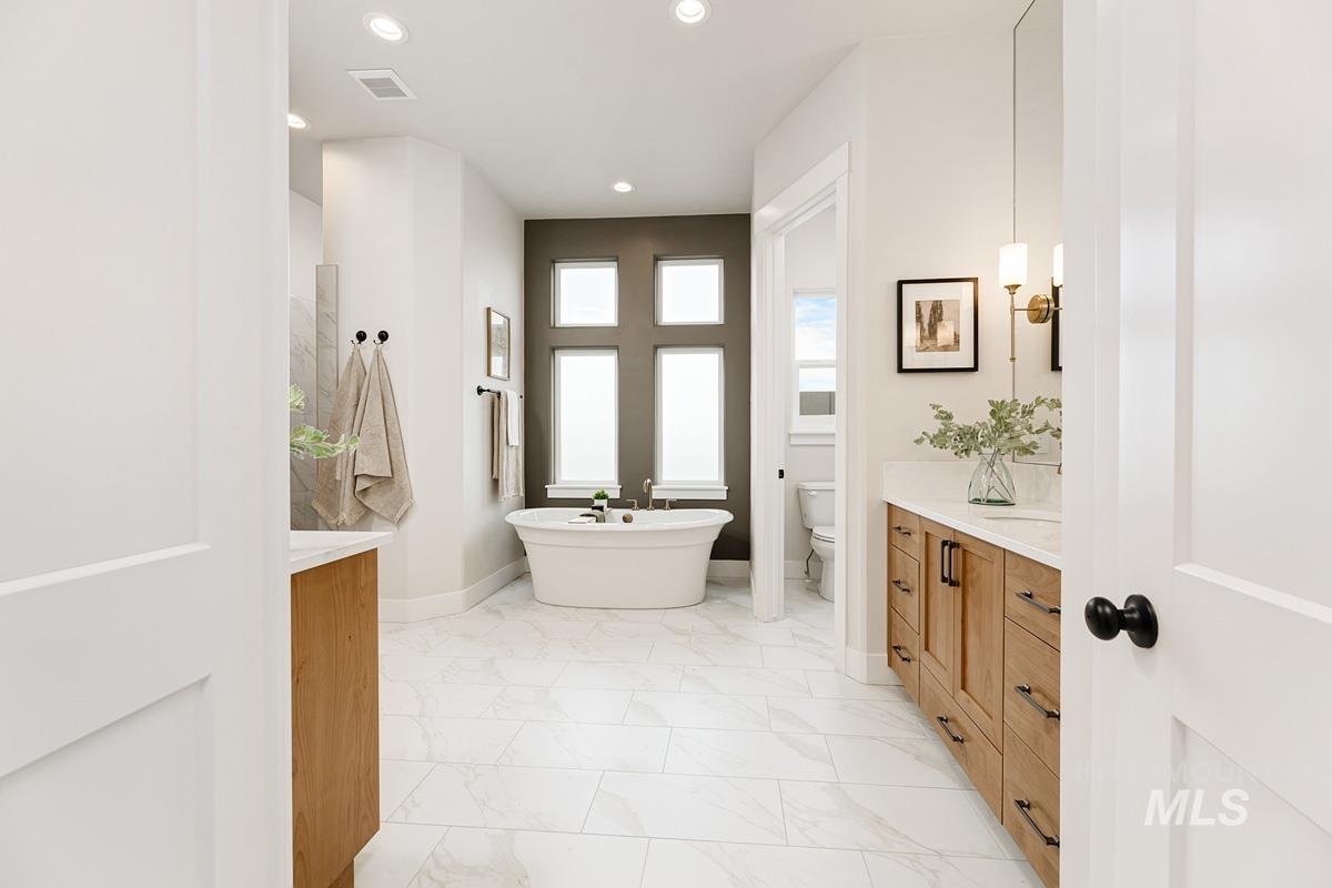Full bathroom featuring vanity, a freestanding bath, light marble finish flooring, and recessed lighting