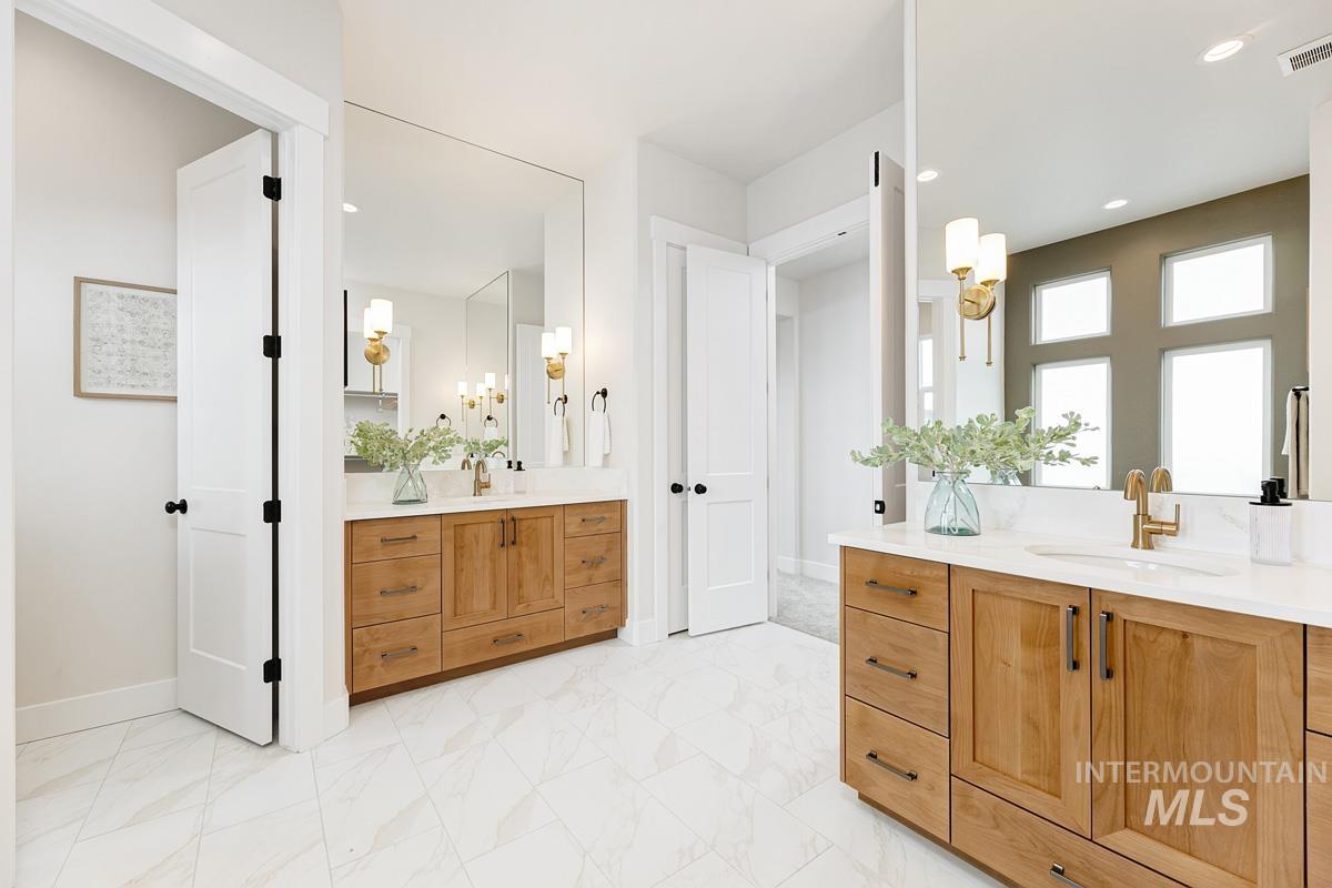 Bathroom featuring light marble finish floors, two vanities, and recessed lighting