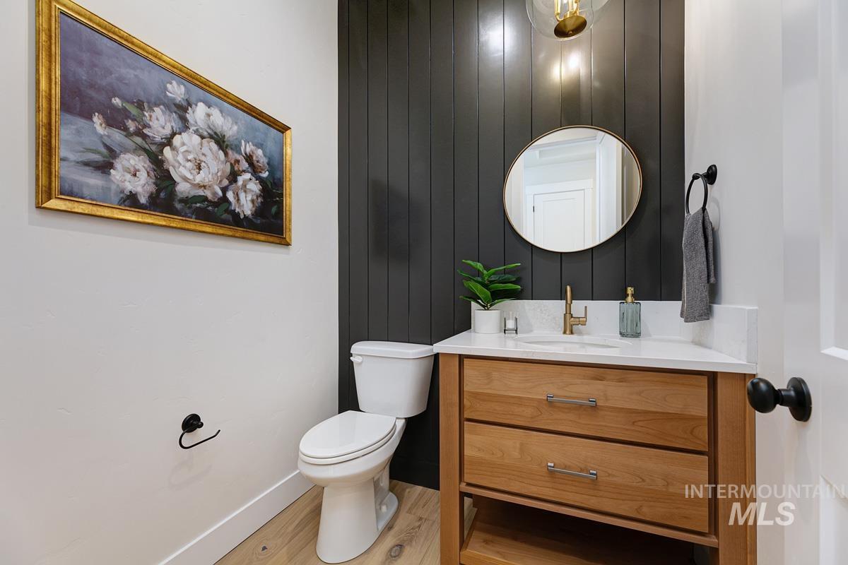 Half bath with vanity, light wood-style flooring, and wooden walls