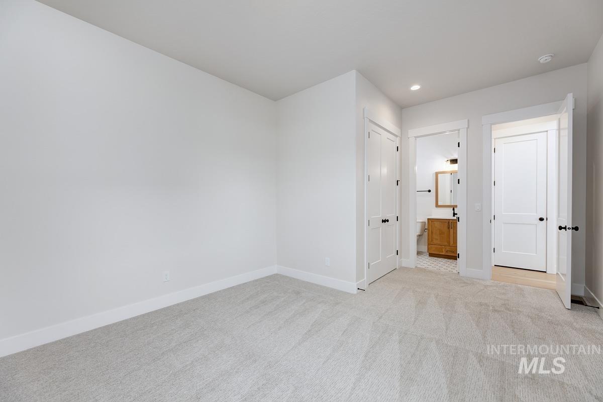 Unfurnished bedroom featuring a closet, light carpet, recessed lighting, and ensuite bathroom