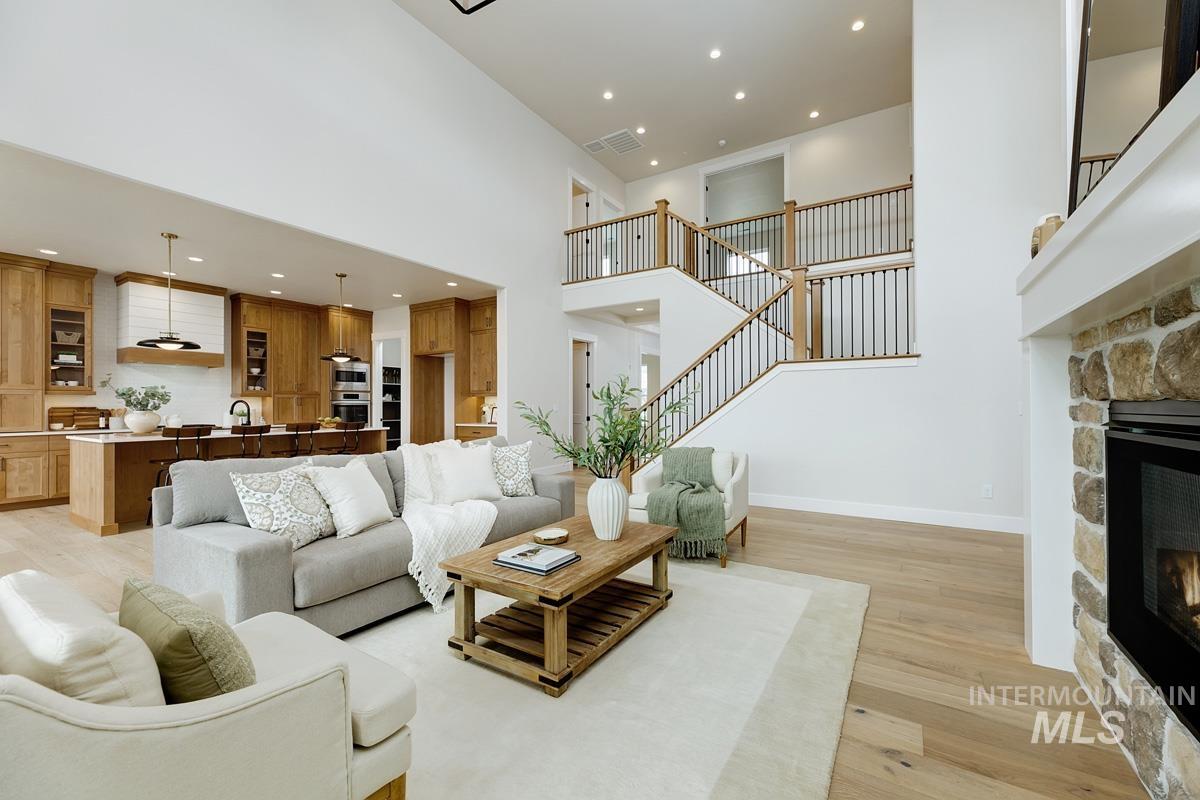 Living area with light wood-type flooring, a fireplace, a high ceiling, recessed lighting, and stairs