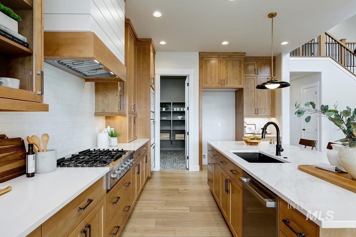 Kitchen featuring brown cabinets, recessed lighting, appliances with stainless steel finishes, pendant lighting, and light stone counters