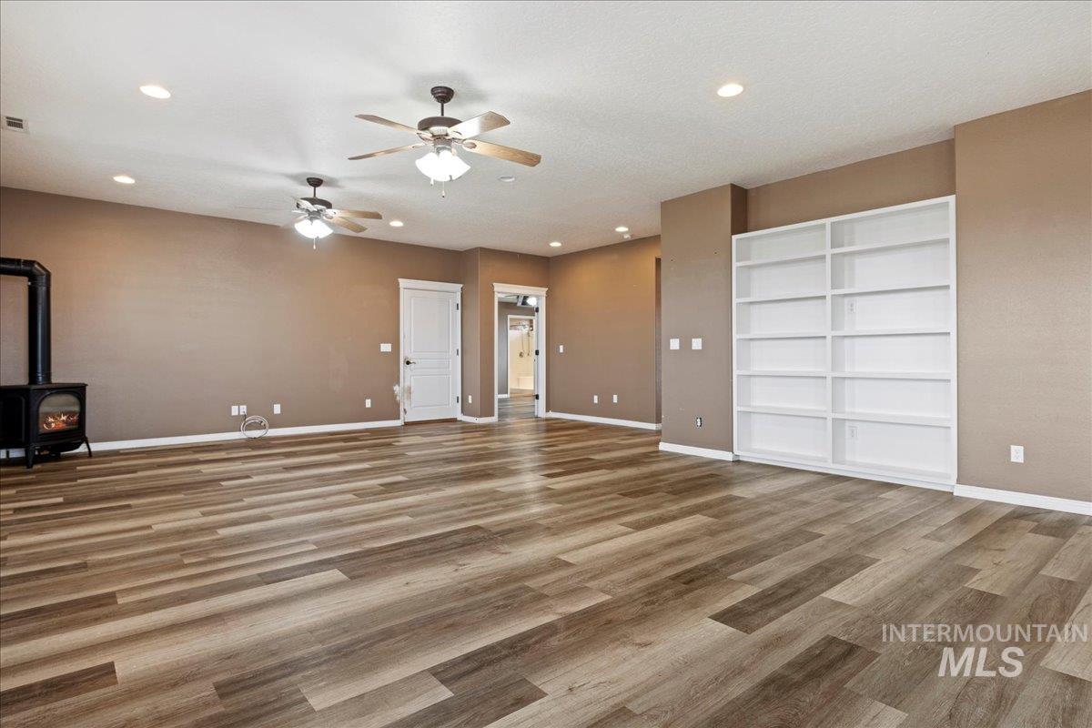 Unfurnished living room with a wood stove, recessed lighting, light wood-type flooring, built in shelves, and a textured ceiling