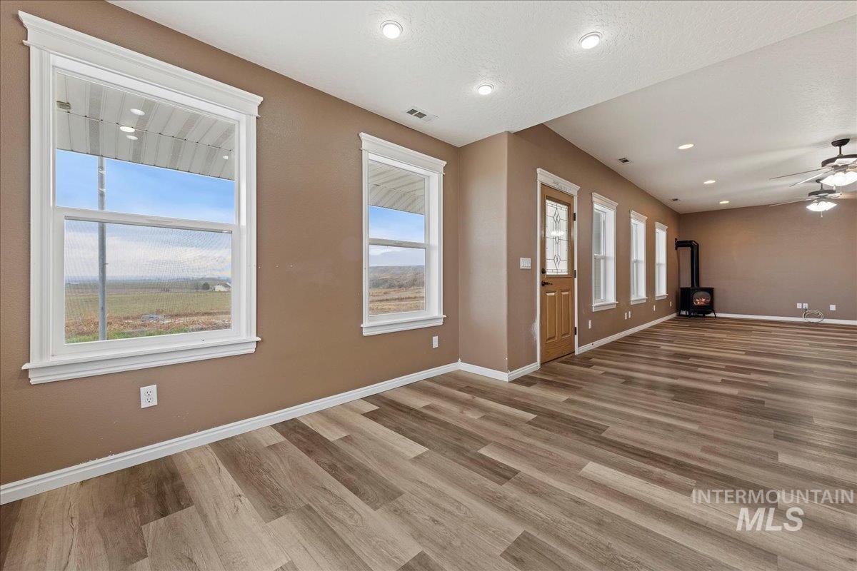 Foyer entrance with a wood stove, wood finished floors, a ceiling fan, recessed lighting, and a textured ceiling