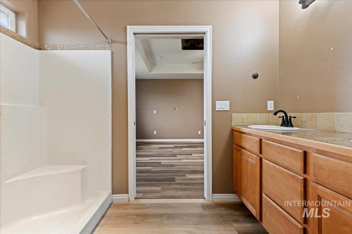 Bathroom featuring vanity, light wood-style floors, and a tile shower