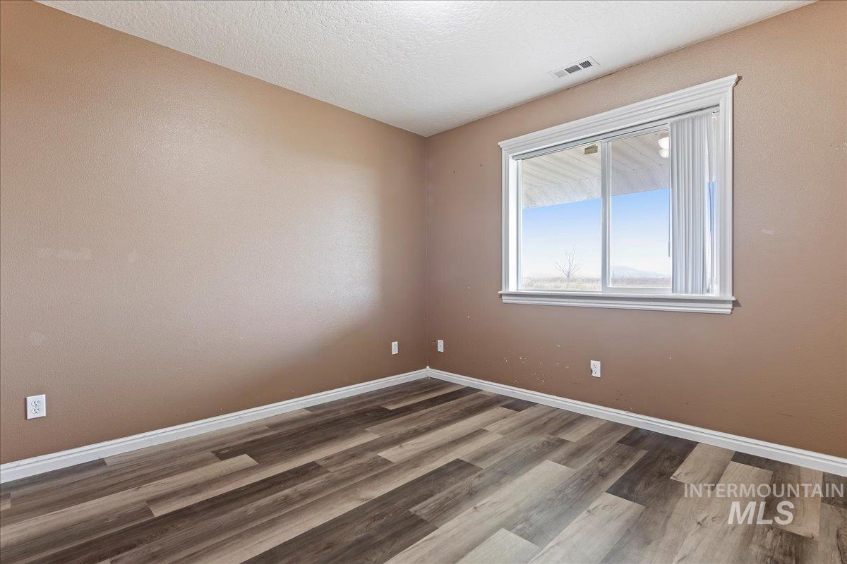 Empty room with wood finished floors and a textured ceiling