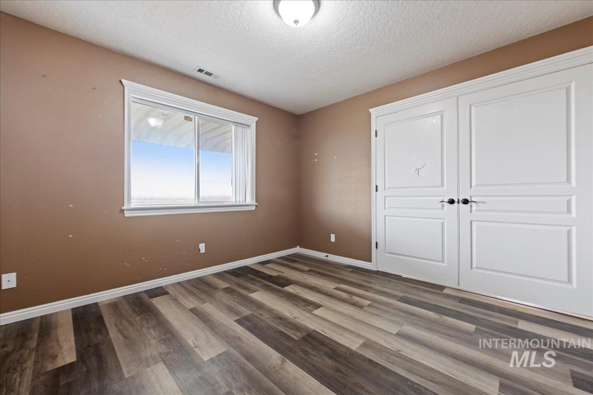 Unfurnished bedroom featuring a textured ceiling, wood finished floors, and a closet