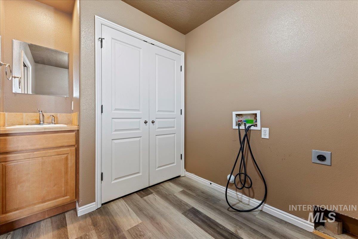 Washroom featuring hookup for a washing machine, light wood-style flooring, a textured wall, and electric dryer hookup