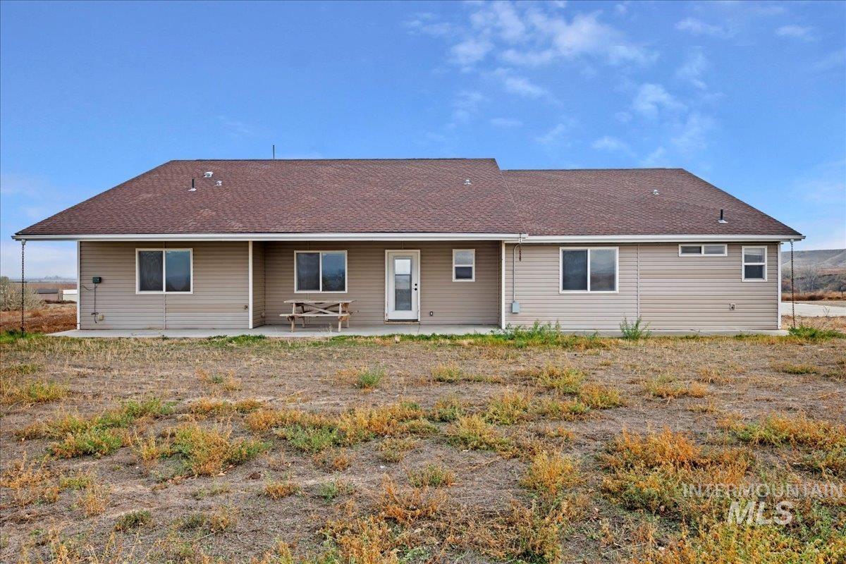 Rear view of house with a patio area and a shingled roof