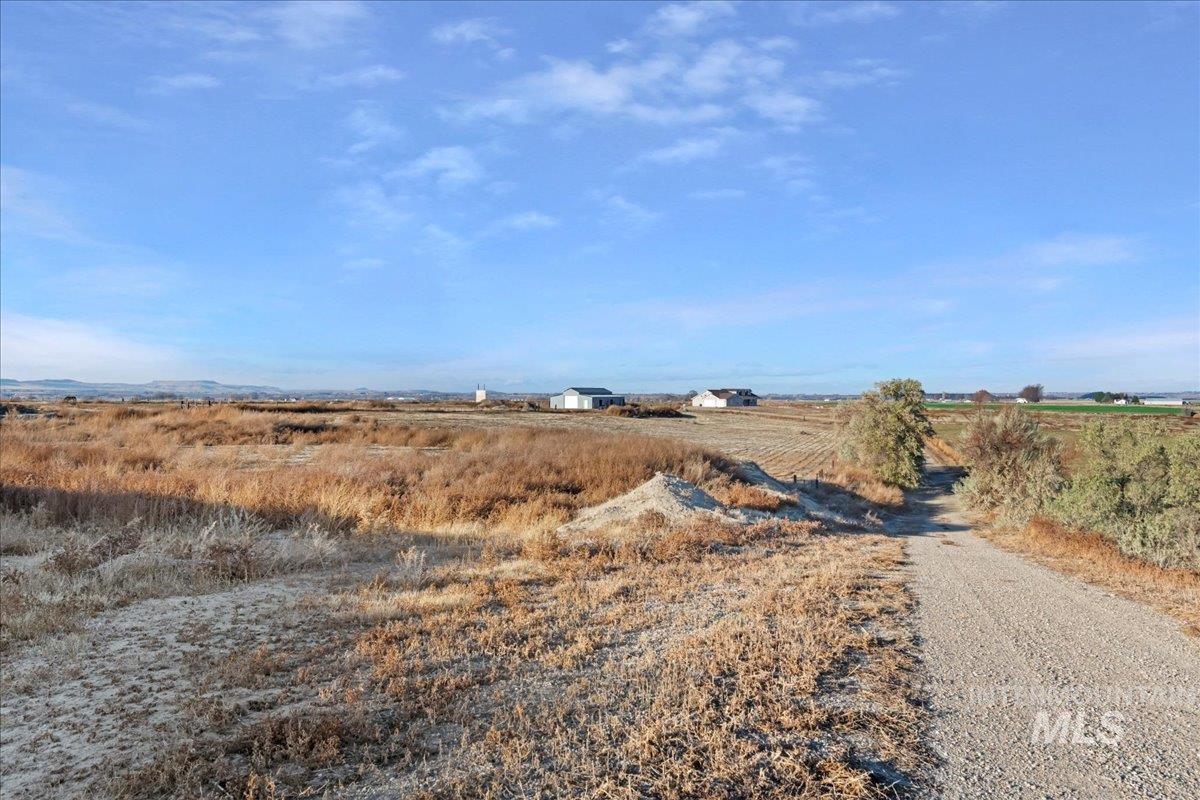 View of dirt / gravel road featuring a view of rural / pastoral area