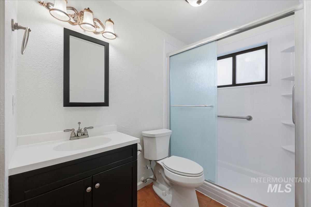 Full bathroom featuring a textured wall, vanity, a stall shower, and tile patterned floors