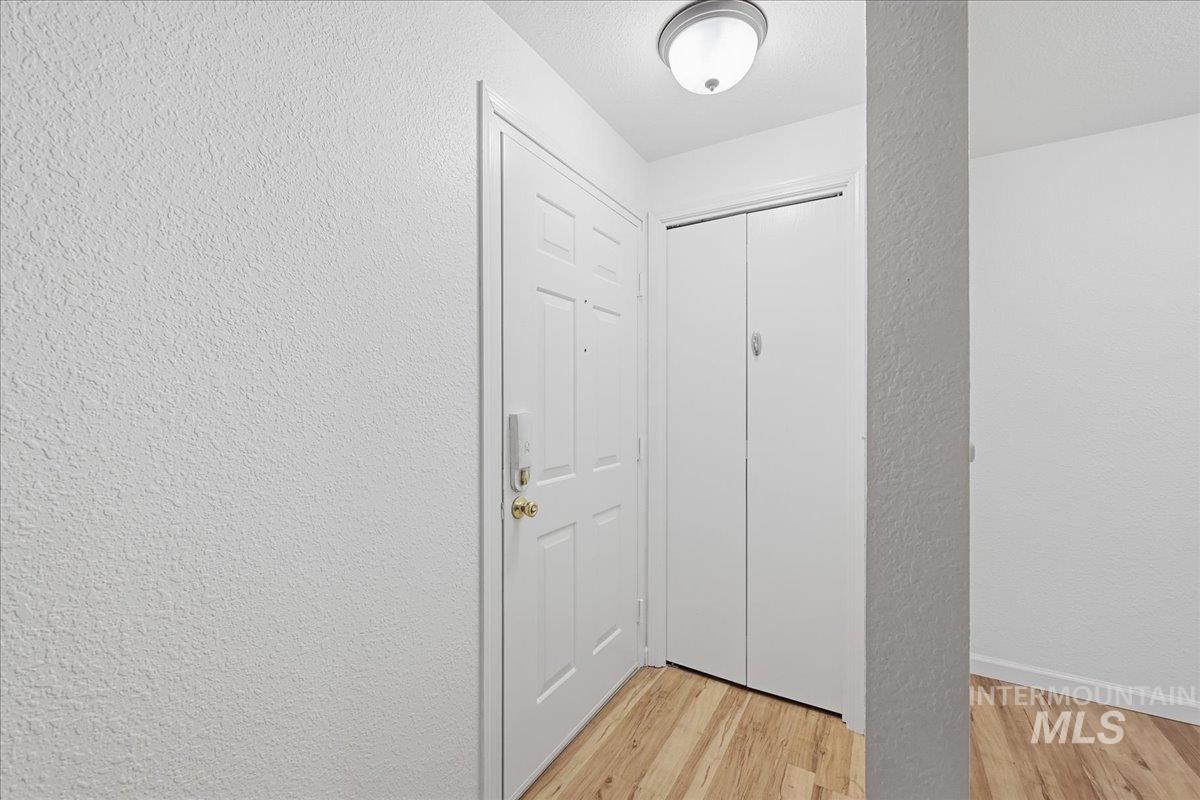 Doorway featuring a textured wall and wood finished floors