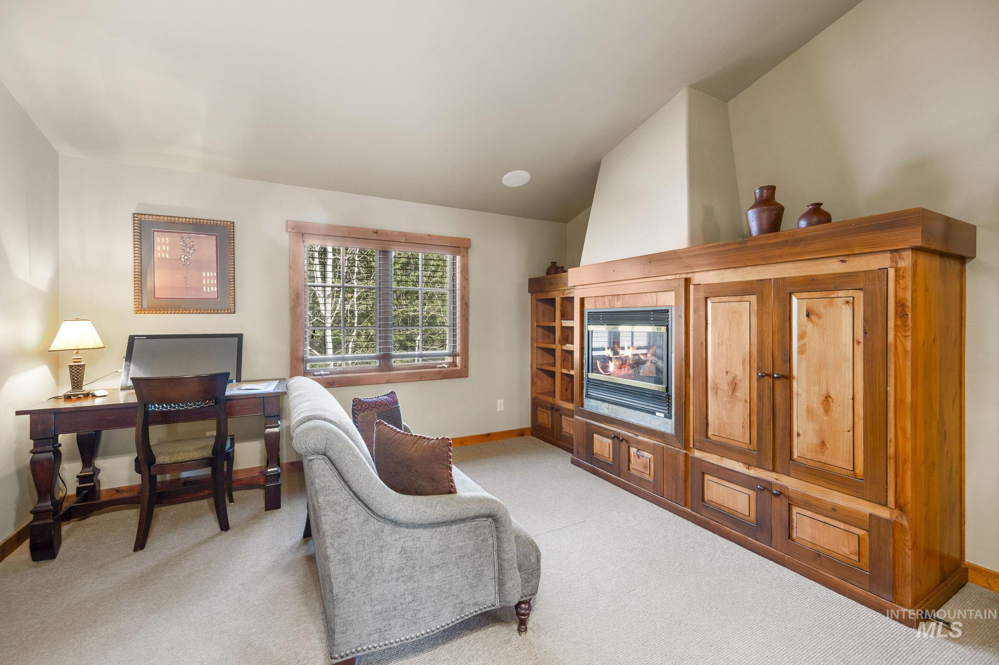 Living area featuring an office area, vaulted ceiling, and light carpet