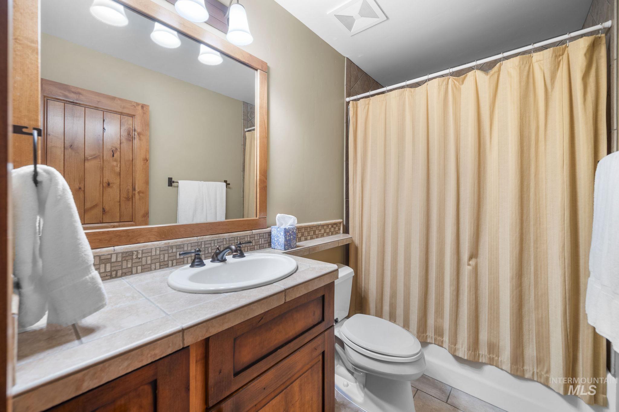 Bathroom featuring vanity, shower / bathtub combination with curtain, and tile patterned floors