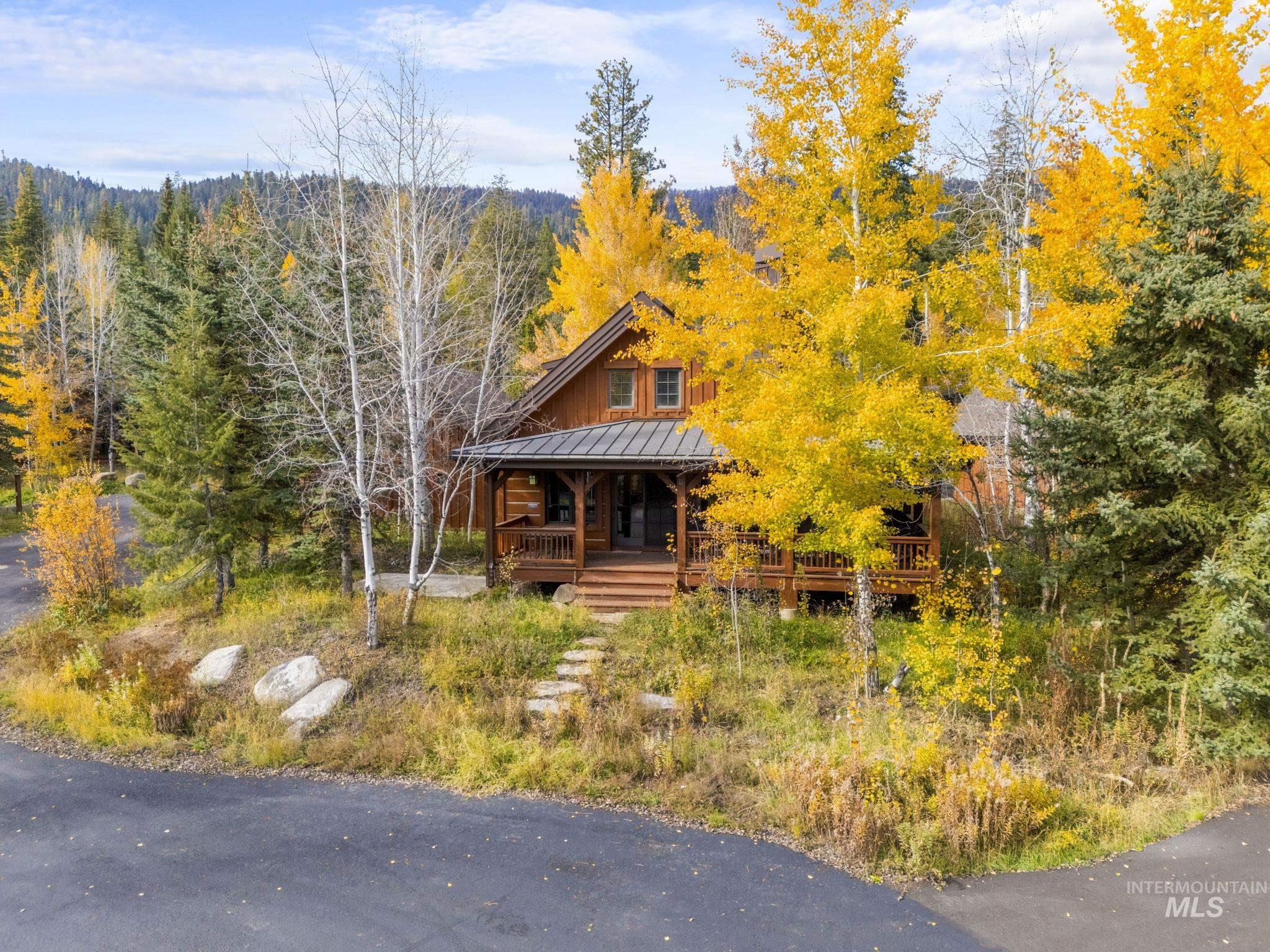 Log-style house with a porch, a metal roof, a standing seam roof, board and batten siding, and a forest view