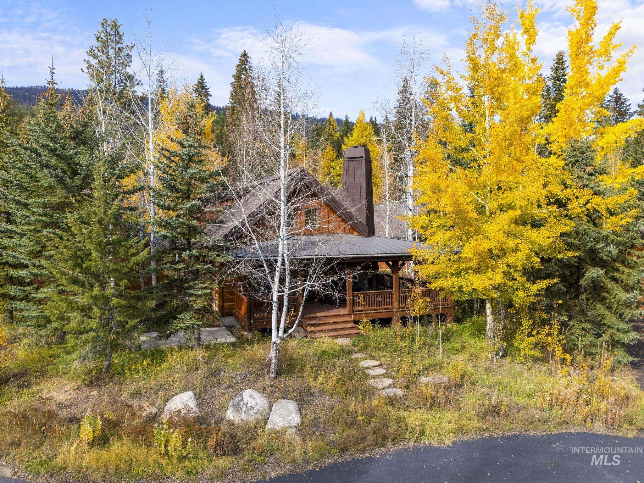 View of front of home featuring a wooden deck, a wooded view, and a chimney