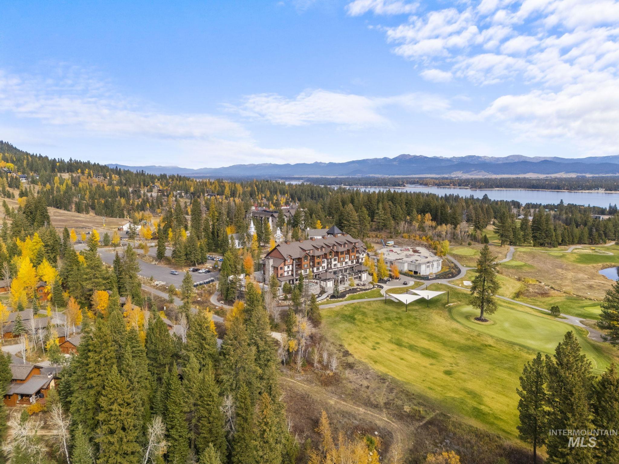 Aerial view of property and surrounding area with a water and mountain view and a golf course
