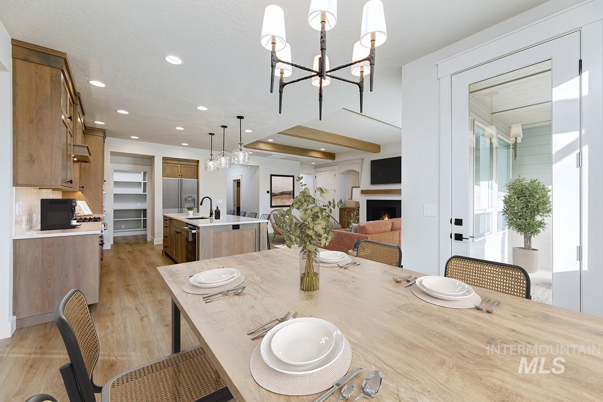 Dining room with light wood finished floors, recessed lighting, a chandelier, and a lit fireplace
