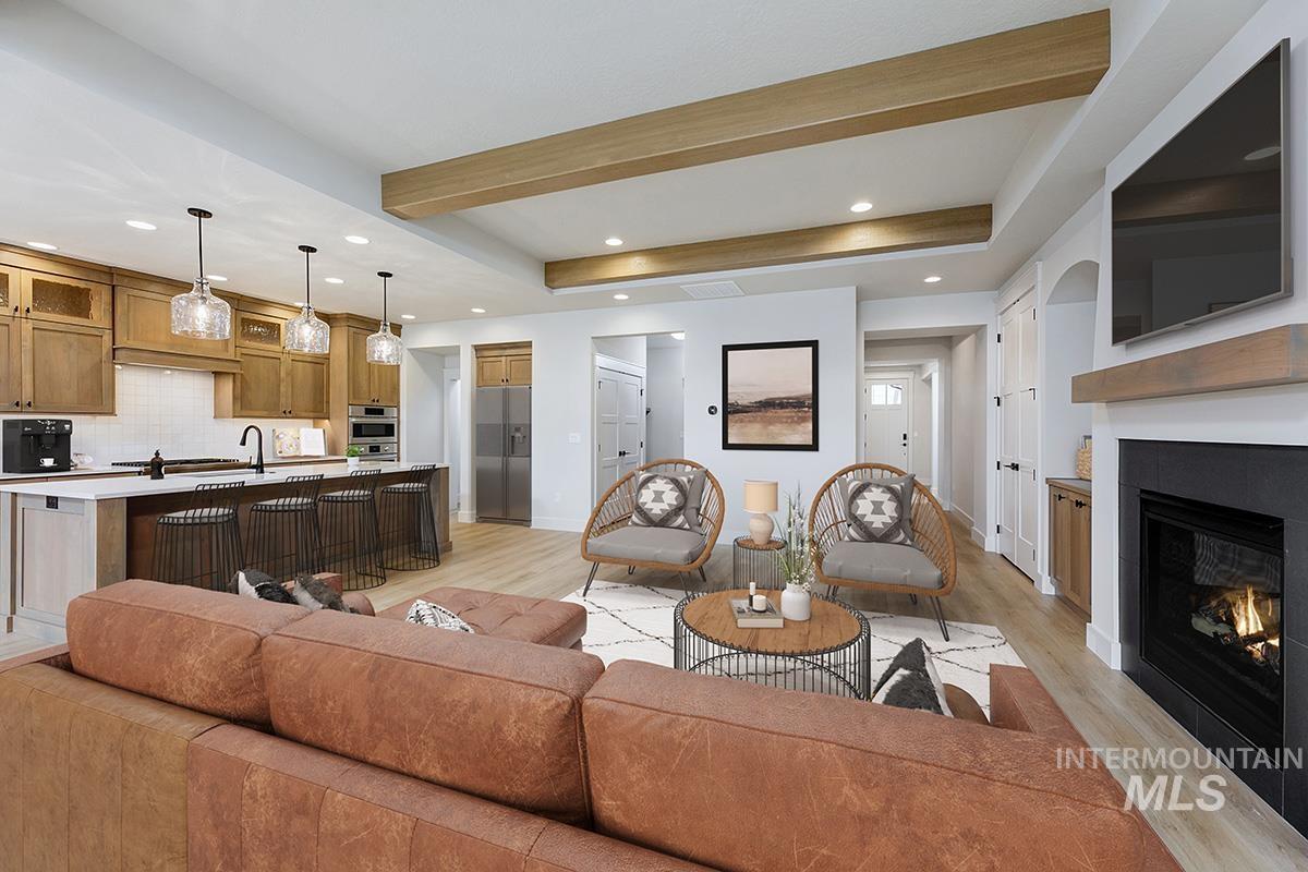 Living room with light wood-style flooring, a glass covered fireplace, beamed ceiling, and recessed lighting