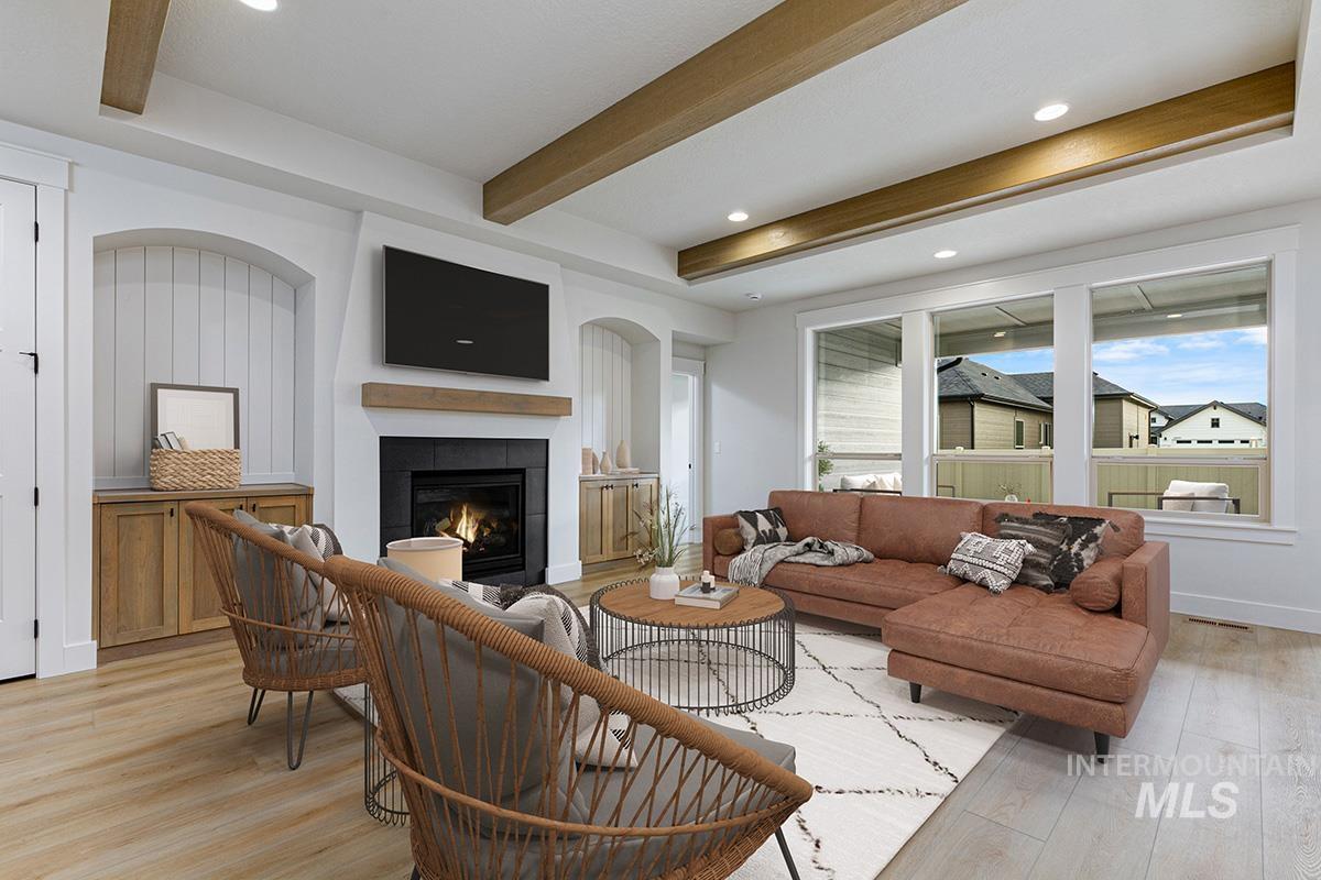 Living room featuring light wood-style floors, beam ceiling, a fireplace, and recessed lighting