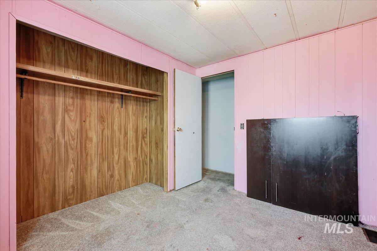 Unfurnished bedroom with wood walls, carpet floors, and a closet
