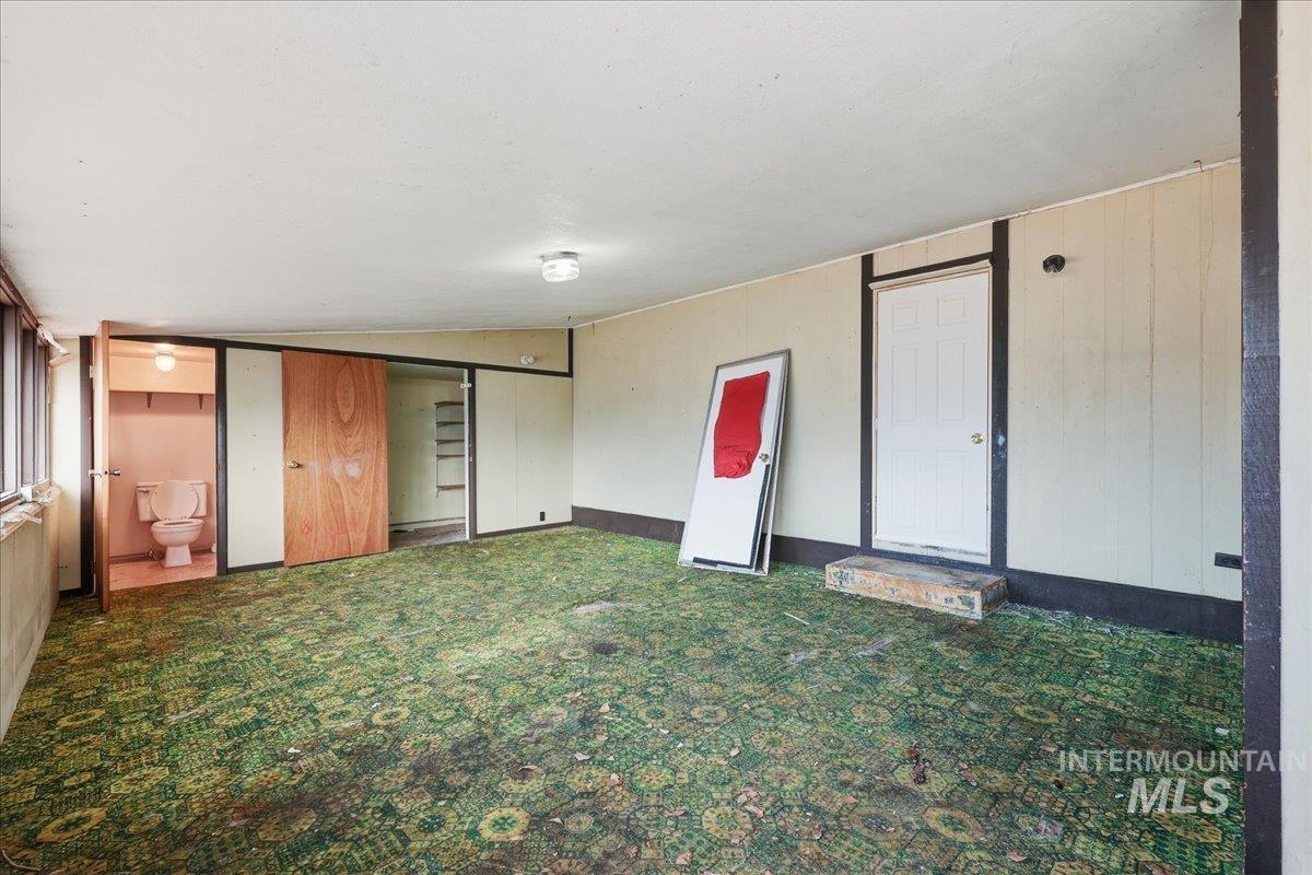 Spare room featuring carpet and vaulted ceiling