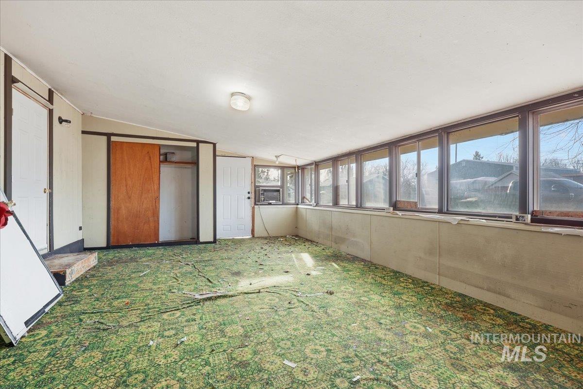 Unfurnished sunroom featuring carpet and vaulted ceiling