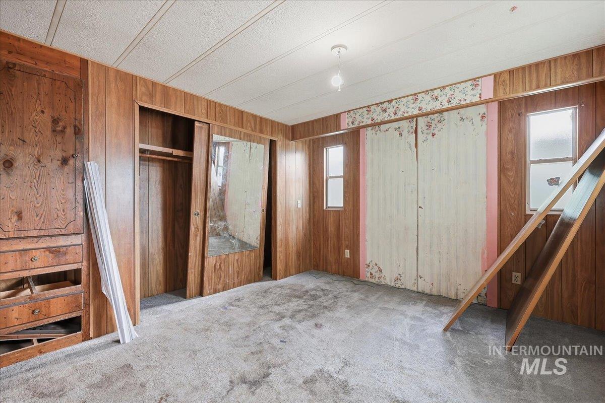 Unfurnished bedroom with carpet flooring, a closet, and wooden walls