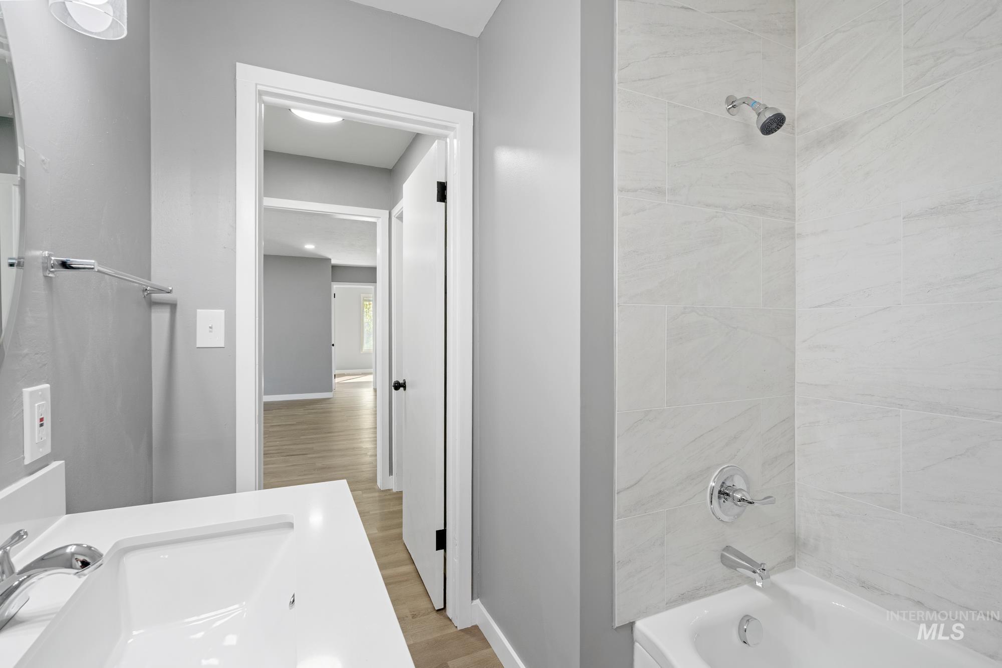 Full bathroom featuring washtub / shower combination, vanity, and light wood-style floors