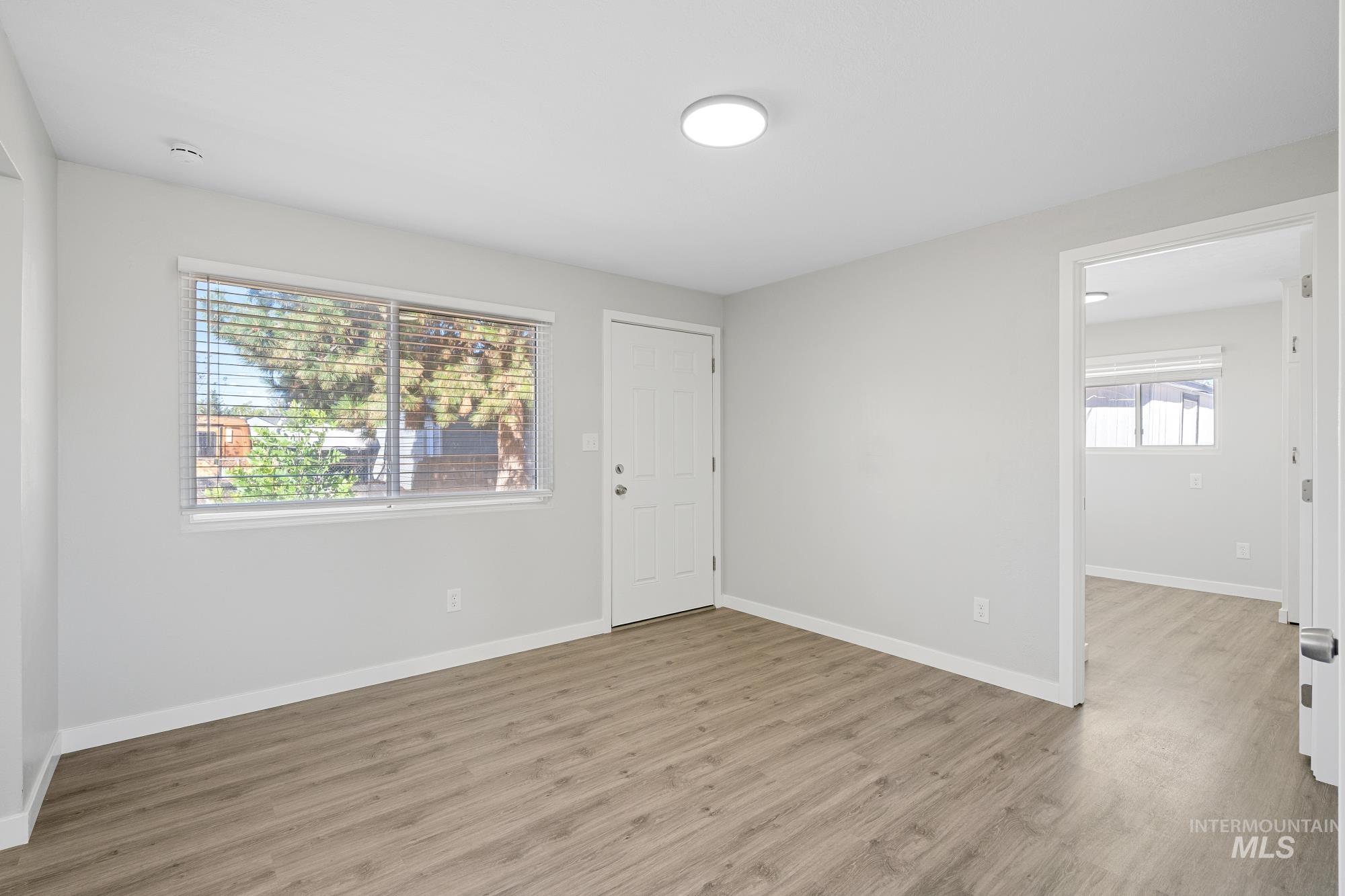 Unfurnished room with light wood-style flooring and baseboards