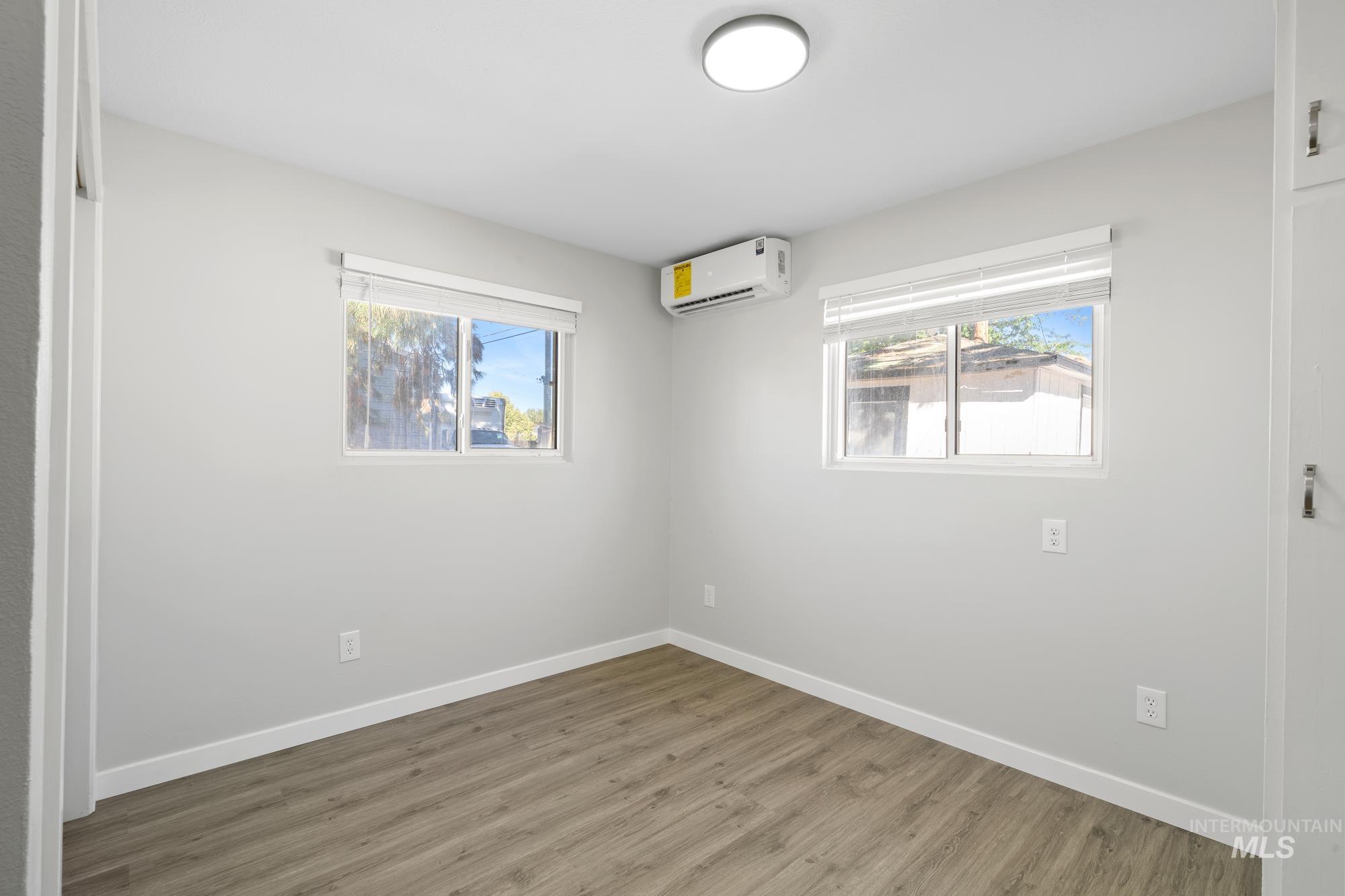 Empty room featuring wood finished floors and a wall mounted AC
