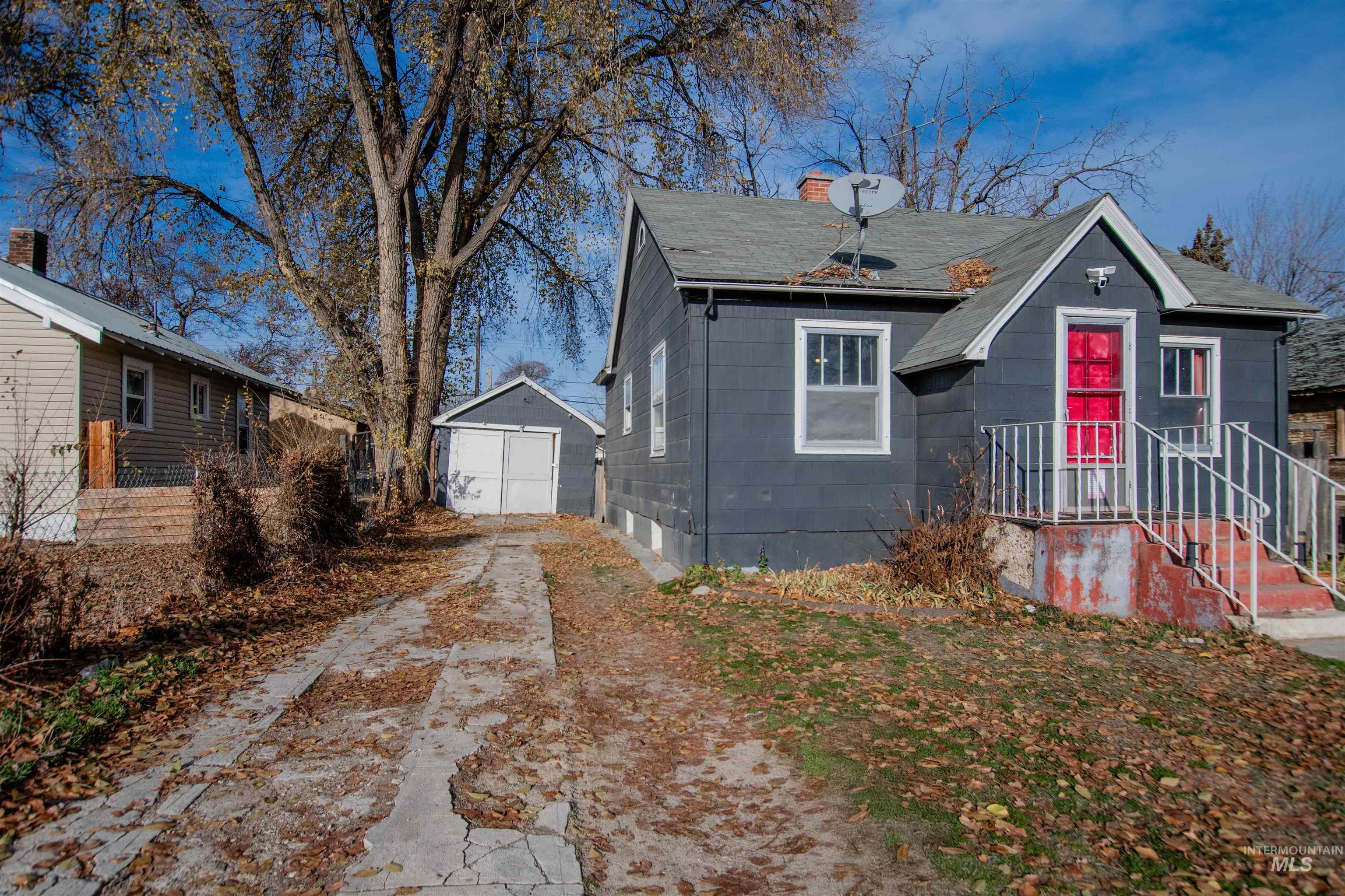 Bungalow-style home featuring a chimney, an outdoor structure, and roof with shingles
