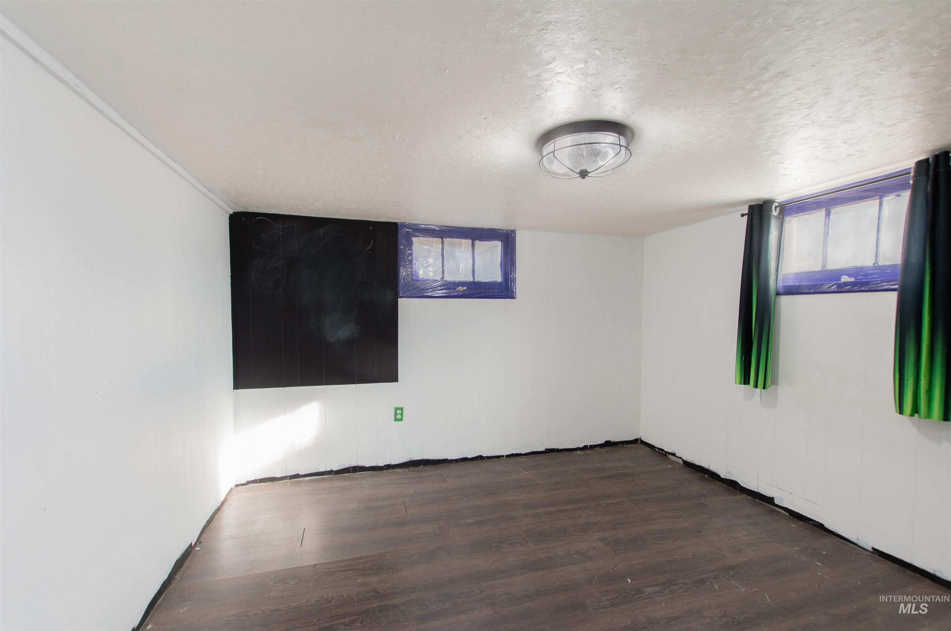 Empty room with a textured ceiling and dark wood-style floors