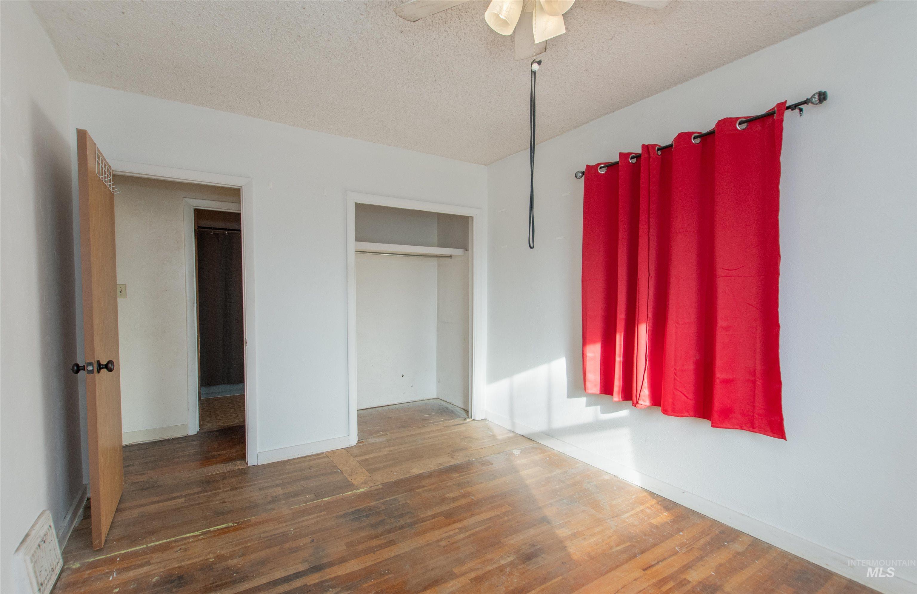 Unfurnished bedroom with a textured ceiling, wood-type flooring, ceiling fan, and a closet
