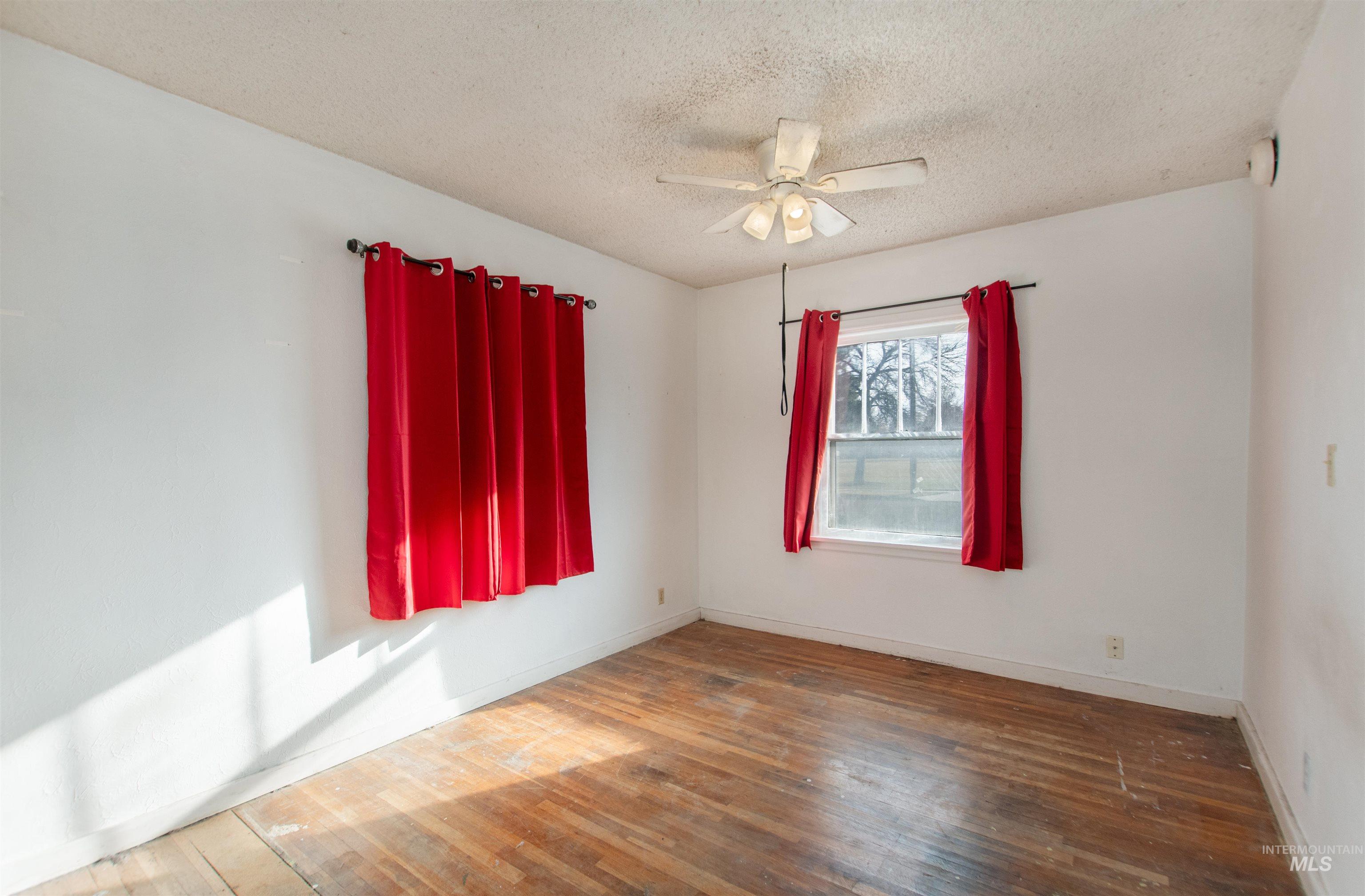 Spare room with a textured ceiling, wood finished floors, and ceiling fan
