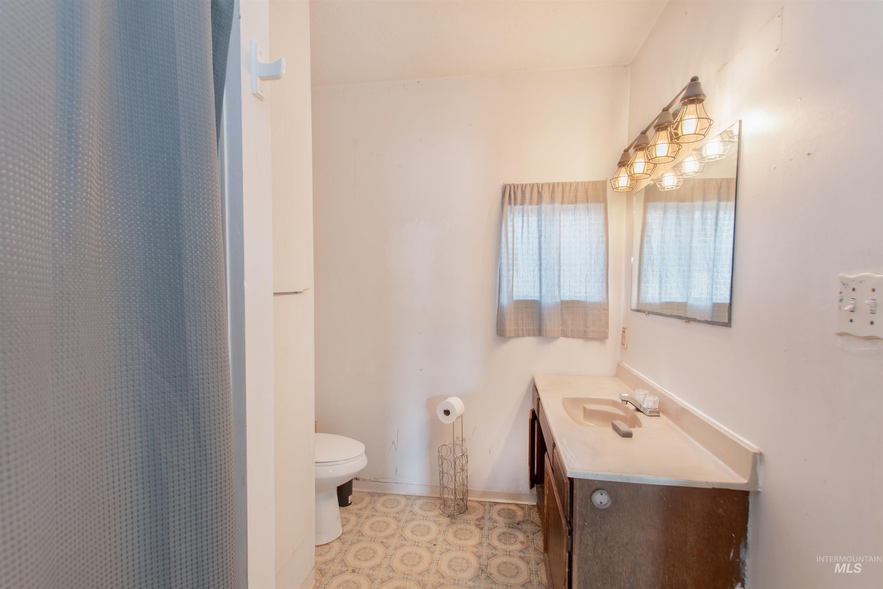 Bathroom with curtained shower, vanity, and light flooring